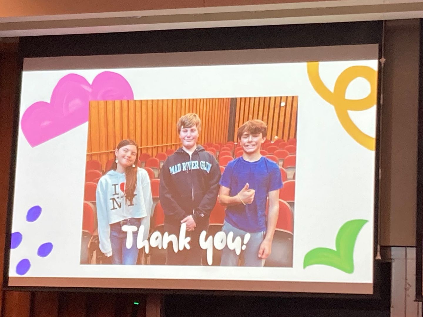 A group of people are standing in front of a screen that says thank you.