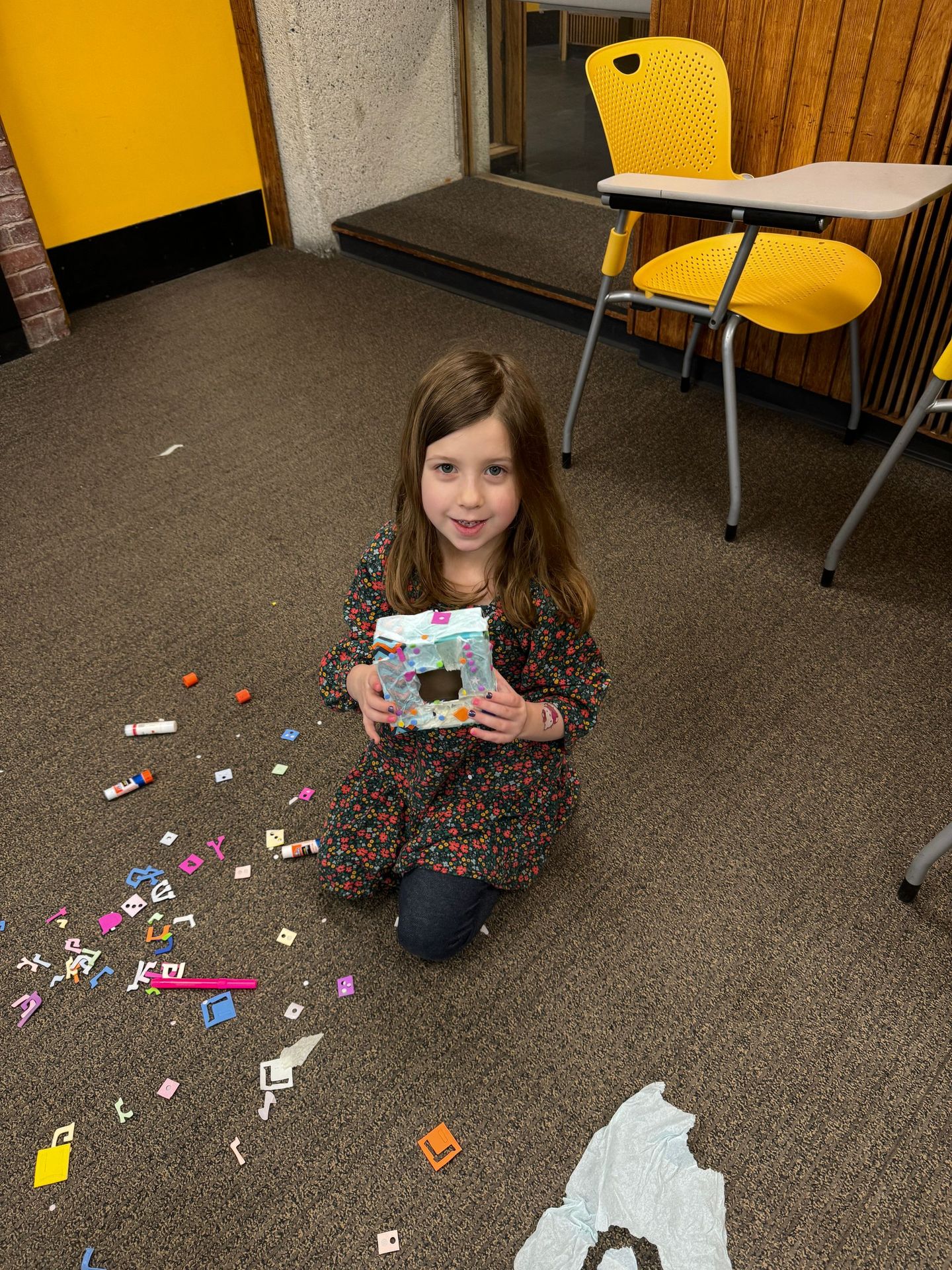 A little girl is sitting on the floor holding a box.