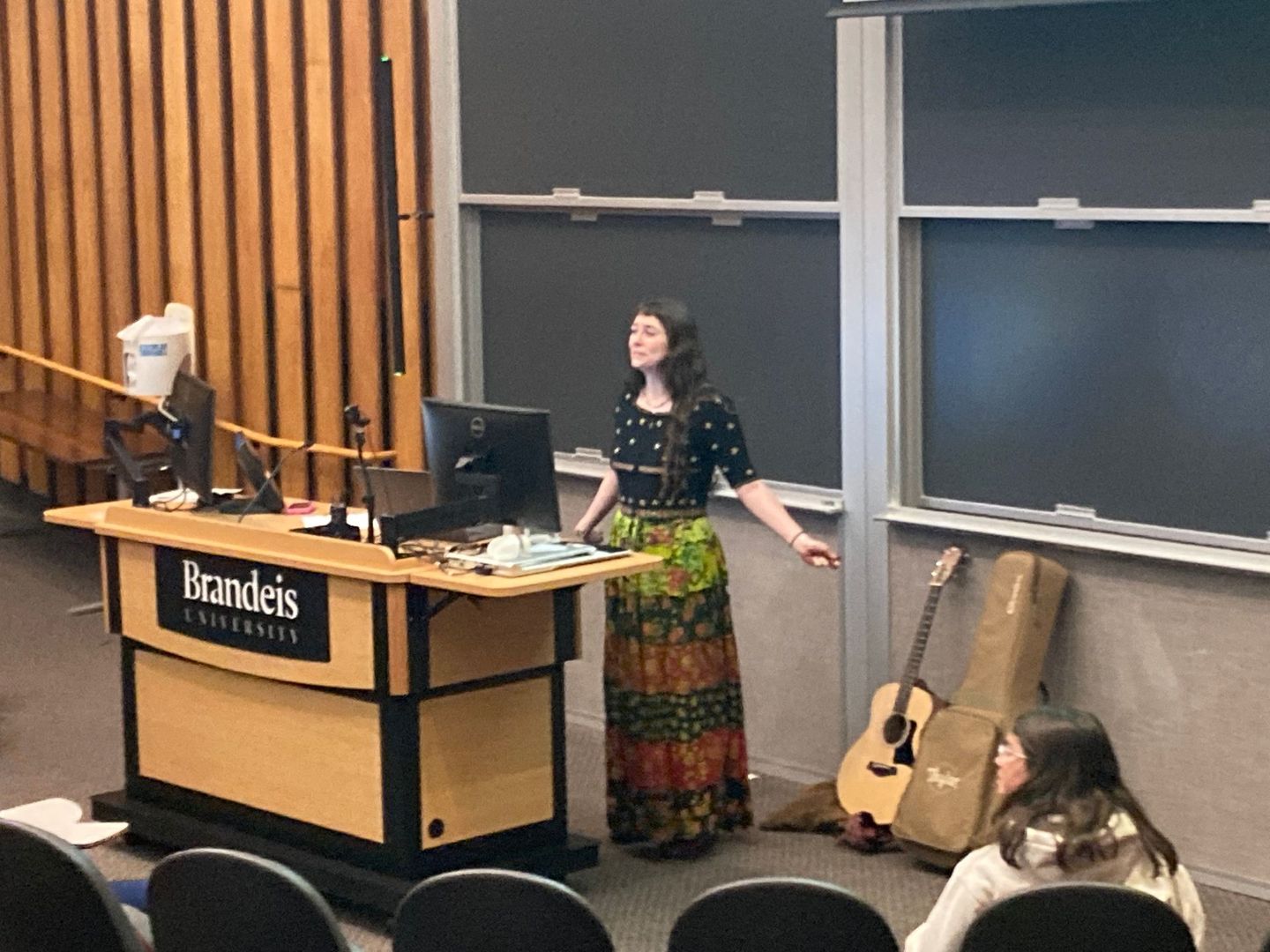 A woman is standing in front of a podium in a lecture hall.