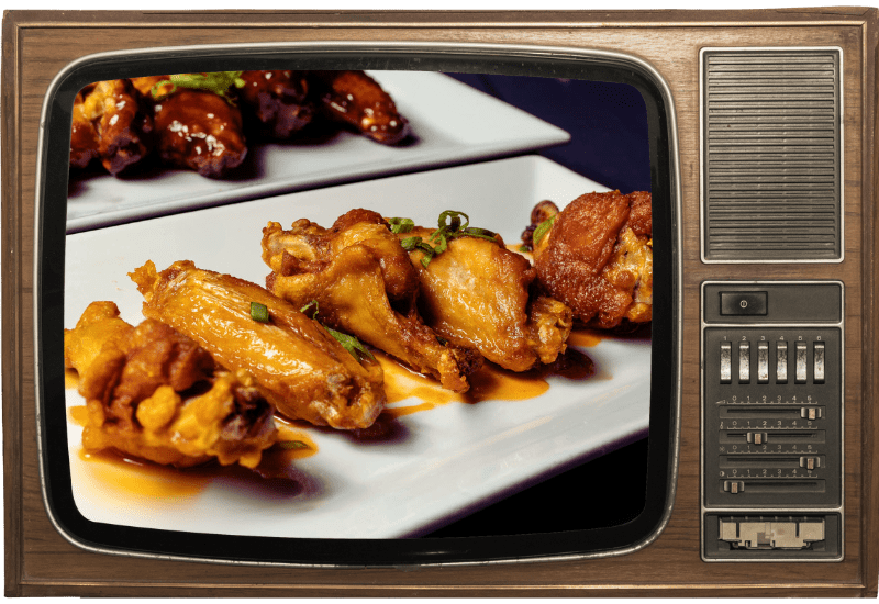 A tv screen shows a plate of chicken wings on it