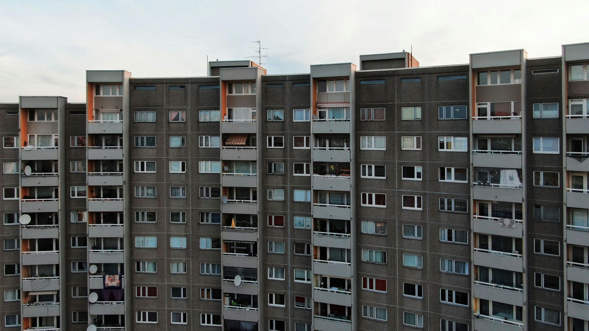Modern multi-story apartment building with geometric design, blue sky background.