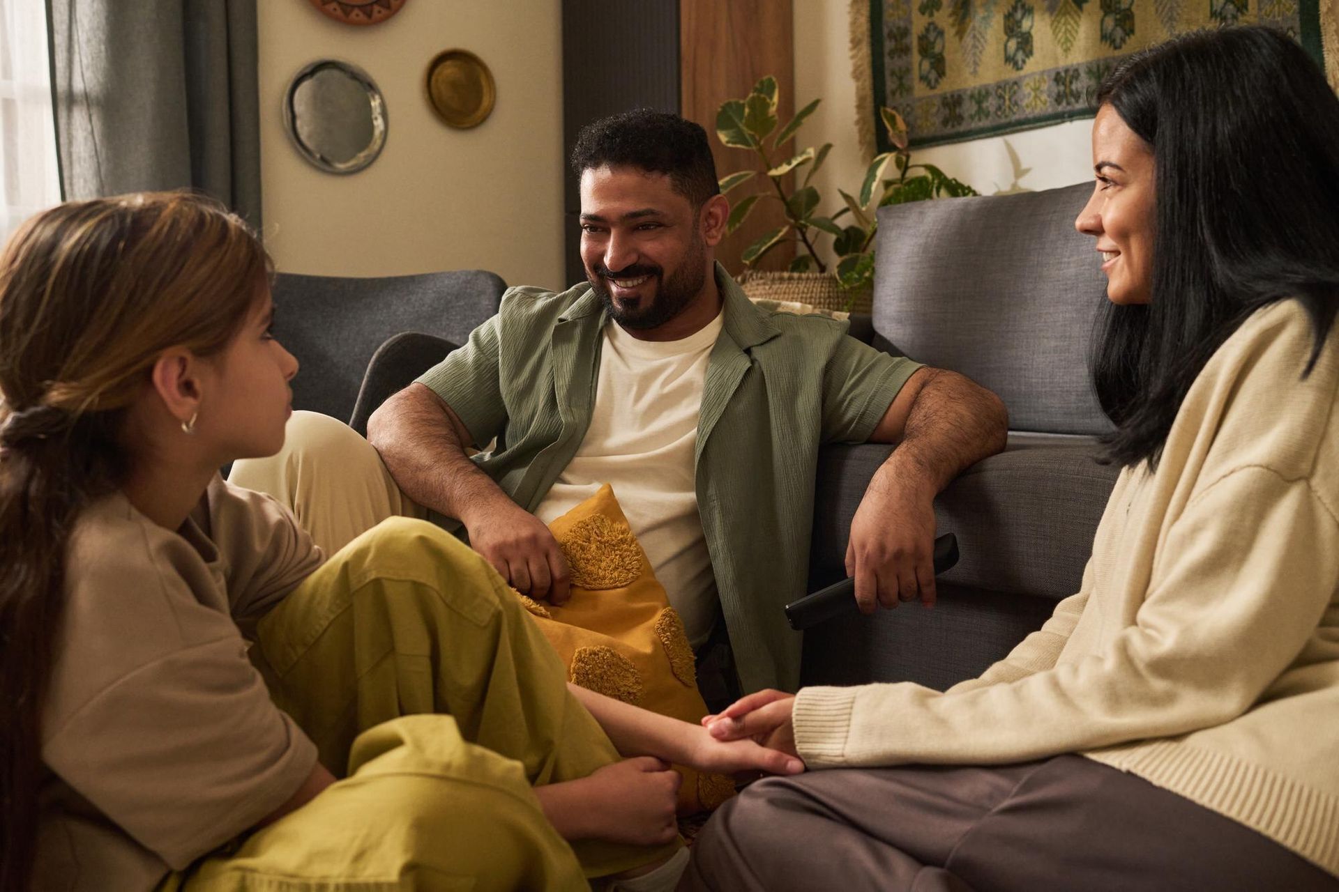 Family sits together in a living room, talking and smiling about mental health