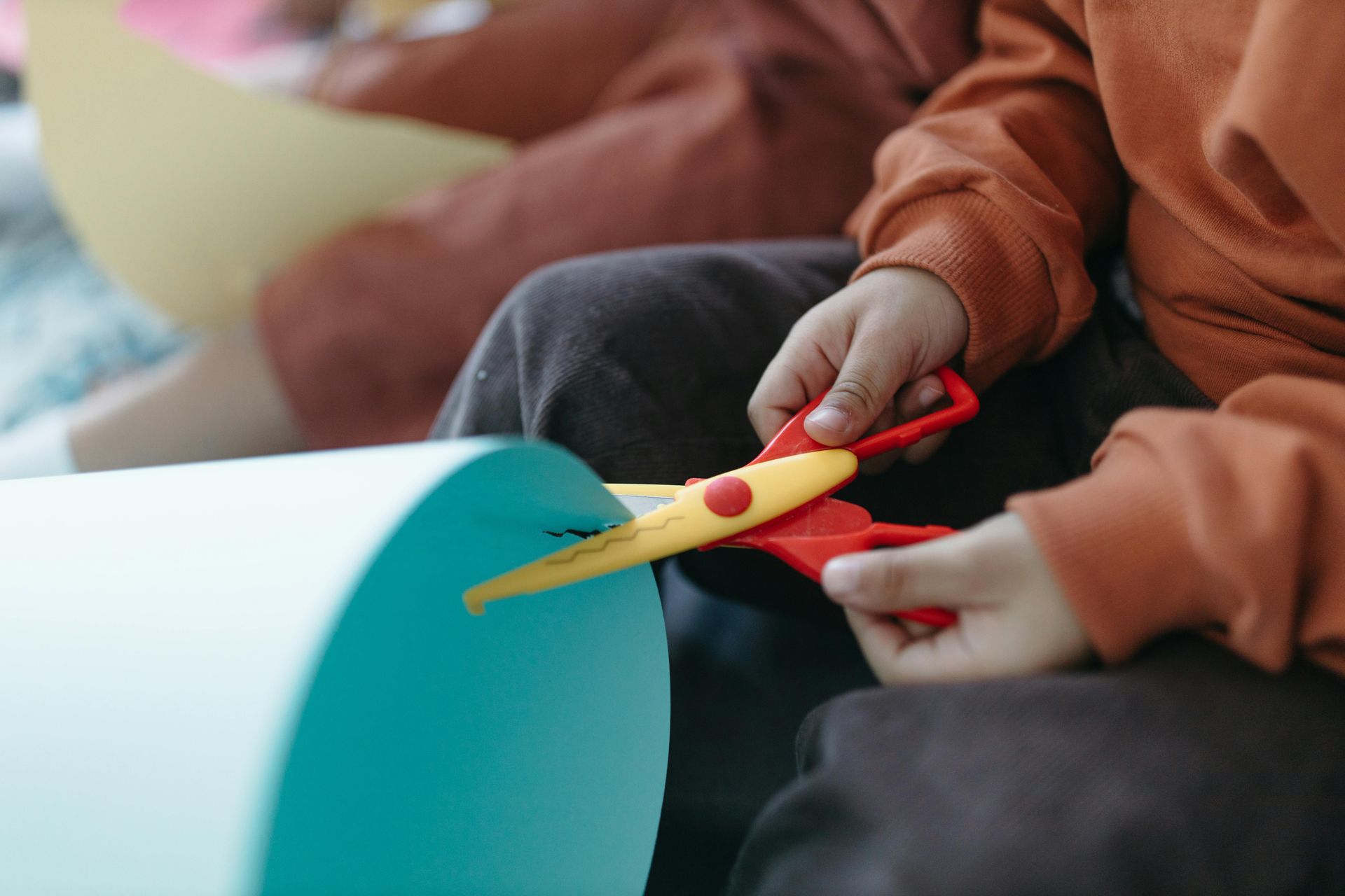Three children sitting on a rug playing with colorful building blocks in a brightly lit room.