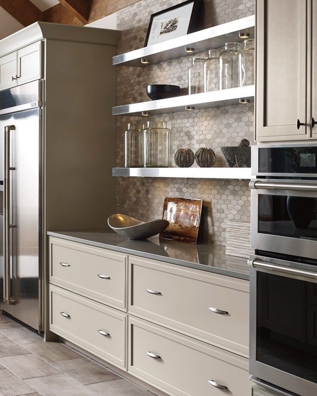 Modern kitchen with light cabinetry, stainless steel appliances, and open shelving displaying decorative items.