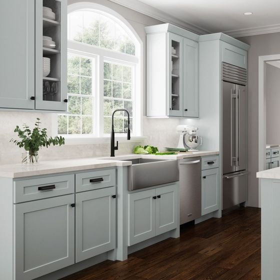 Light blue kitchen with stainless steel appliances and dark wood floor.