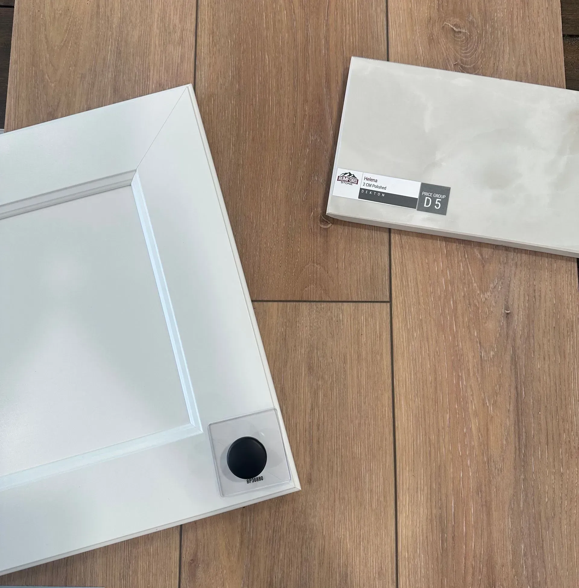 White cabinet door, beige tile, and wood flooring samples.