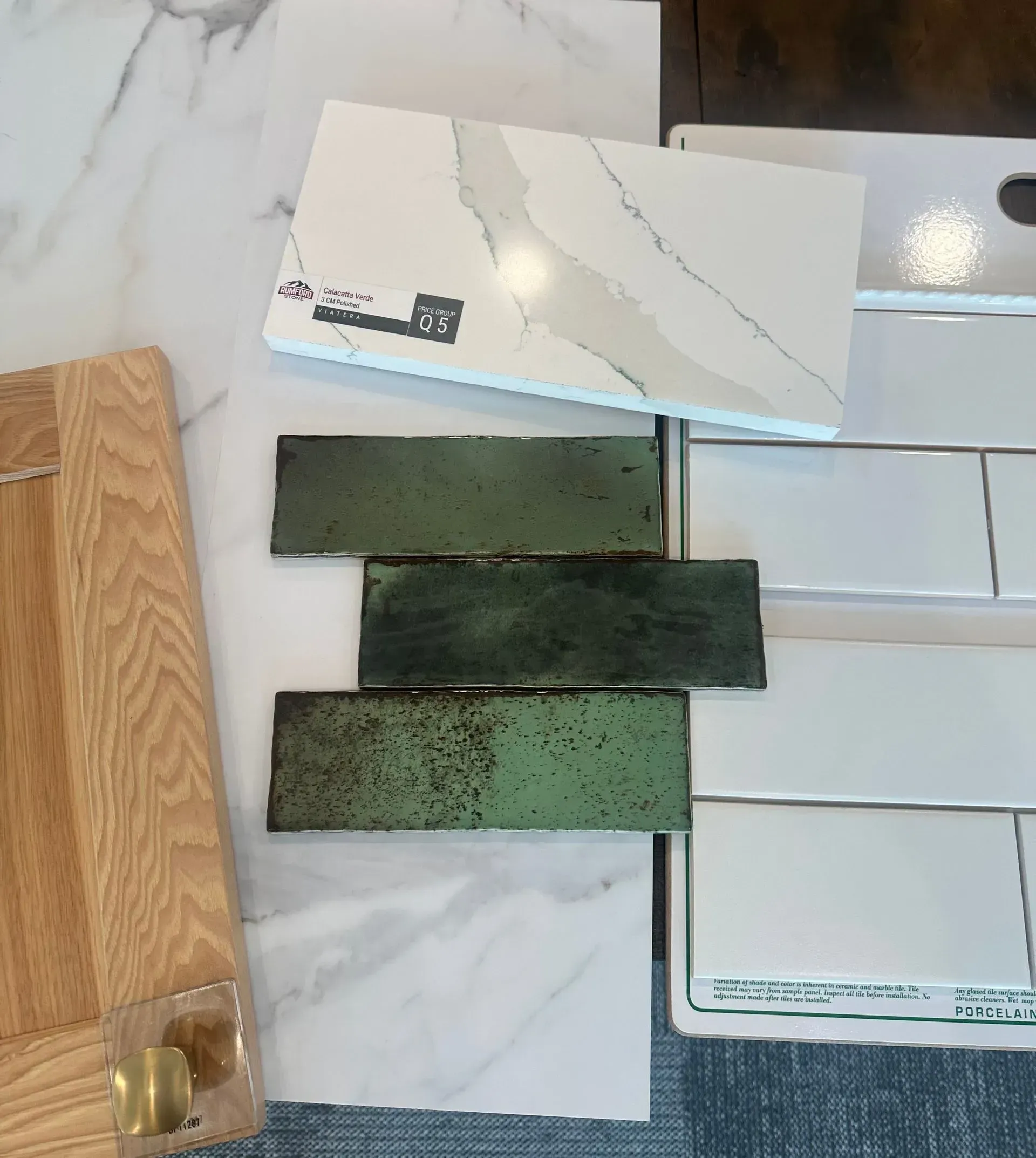Samples of kitchen design elements: wood door, green tiles, white quartz and subway tile.