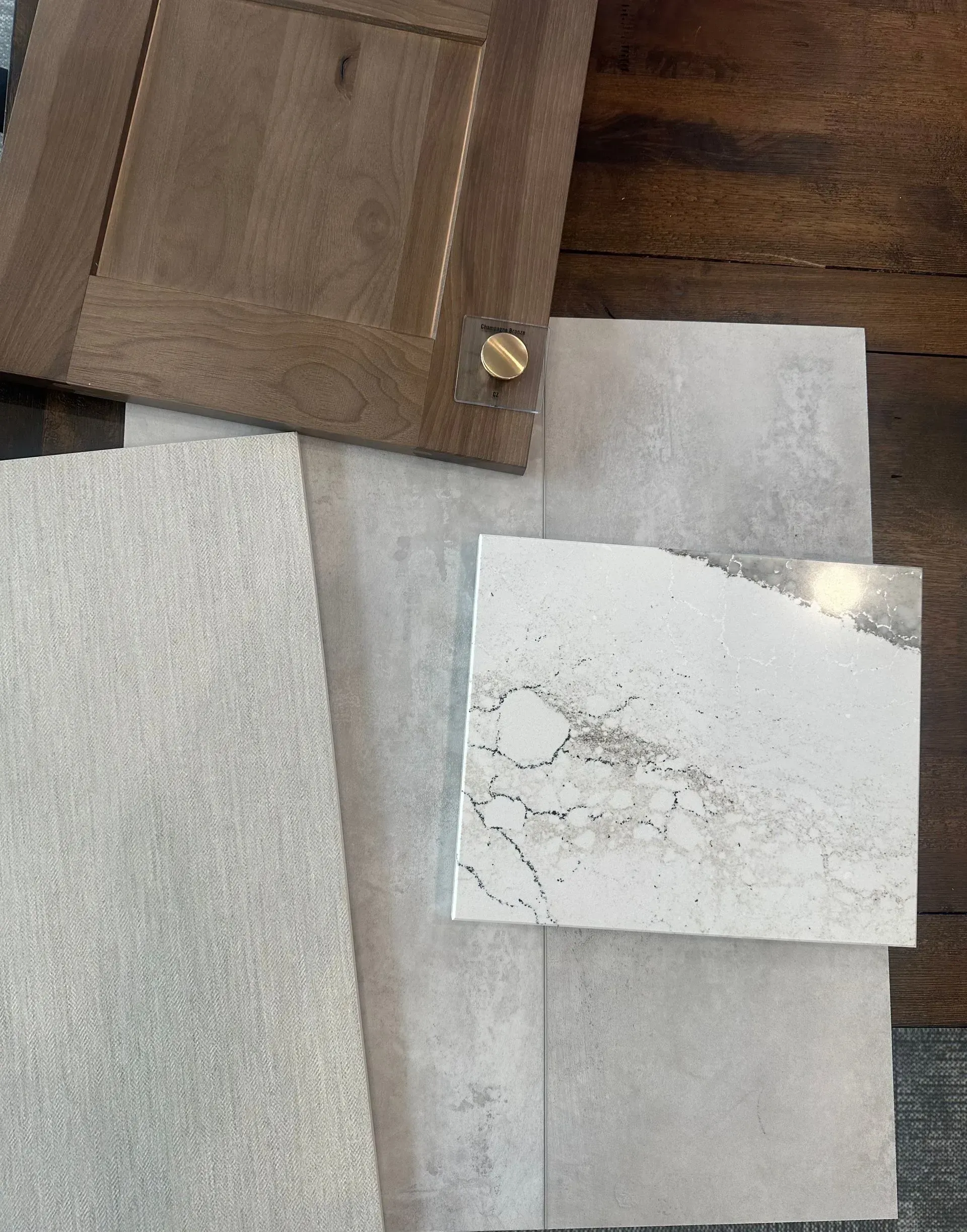 Samples of cabinetry, countertops, and flooring in neutral tones: brown, gray, and white.