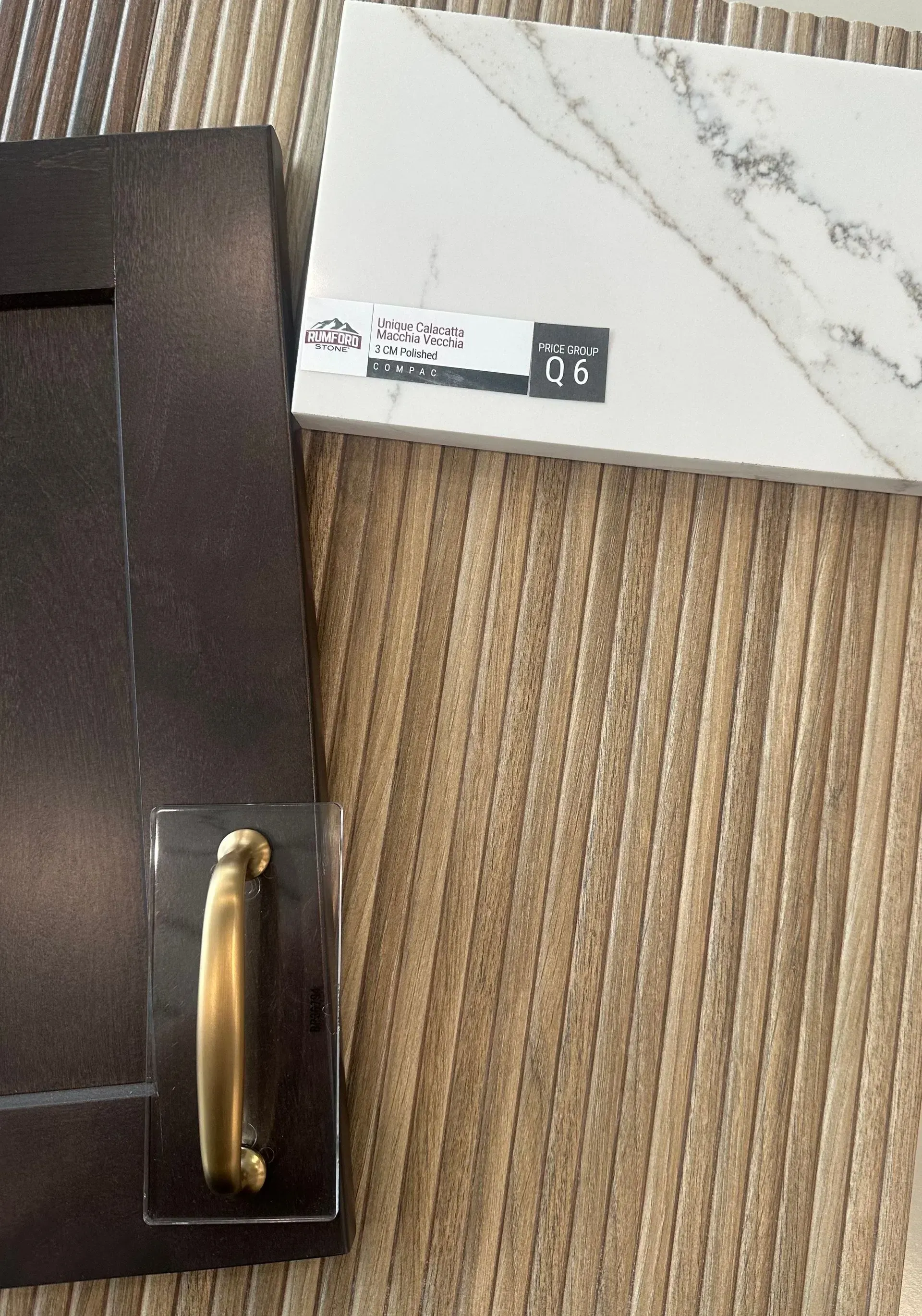 Cabinet door, countertop sample, and brass hardware on a textured background.