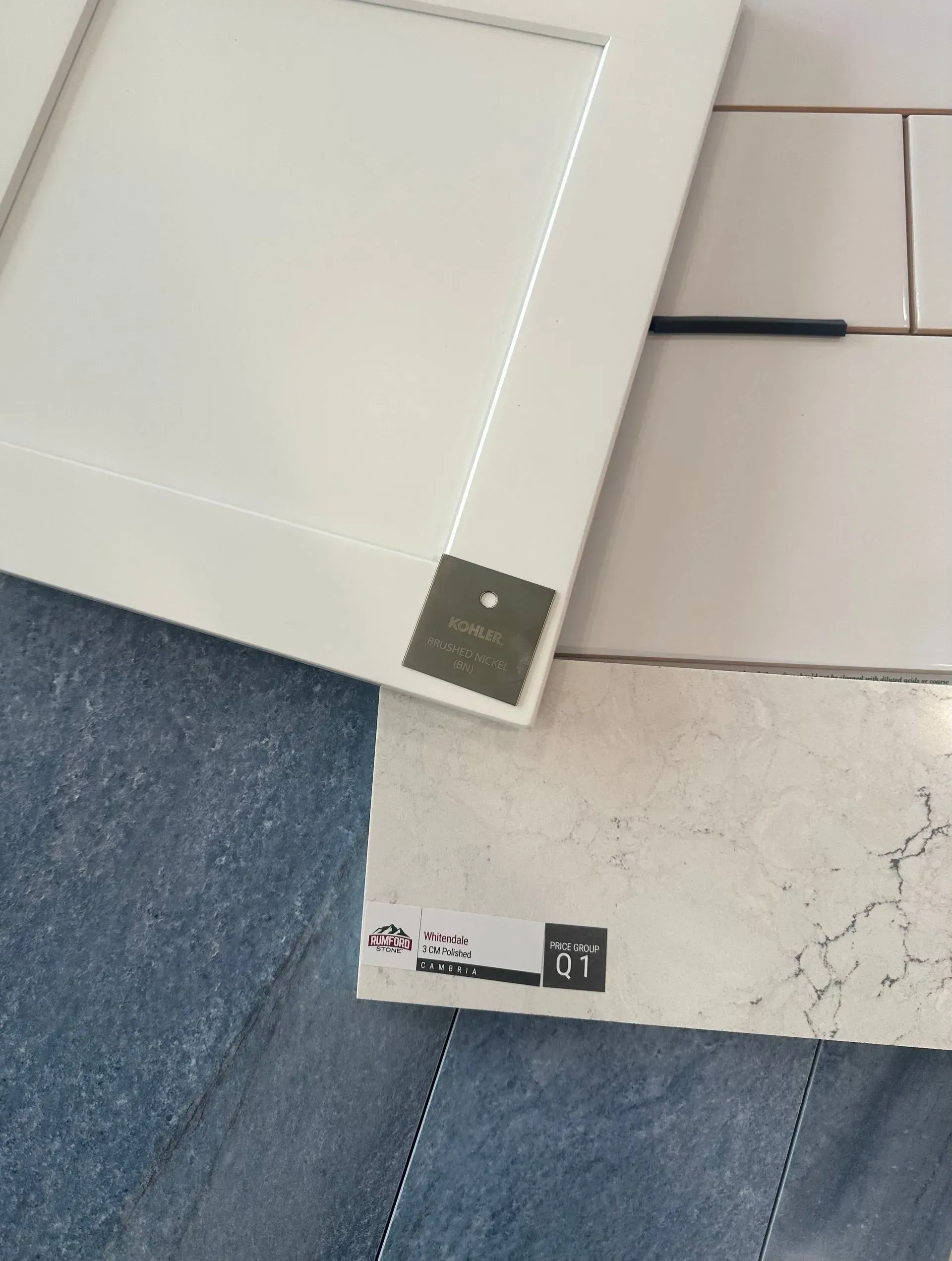 White cabinet door, stone sample, and blue tile, possibly for kitchen design.