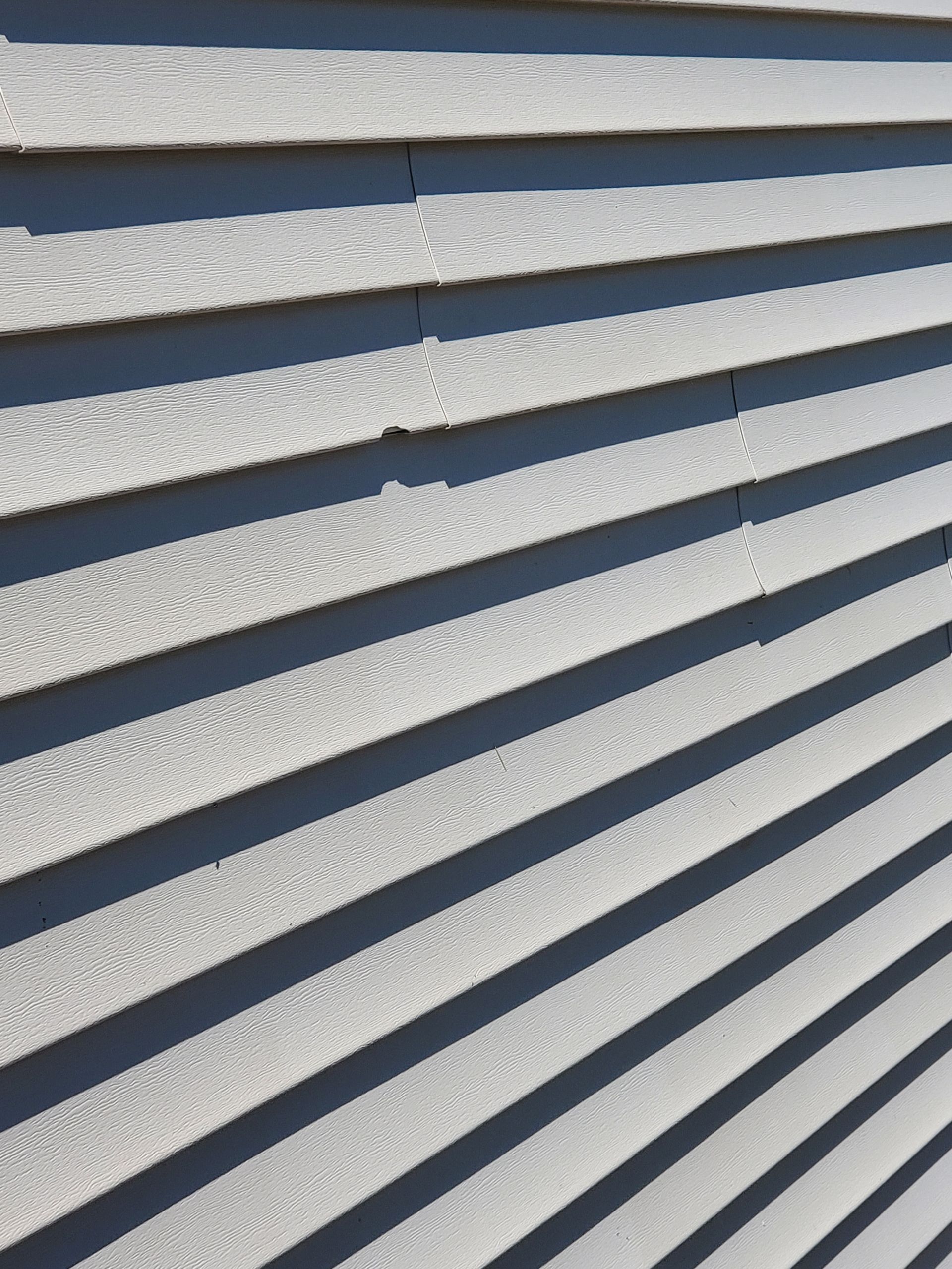 Chipped vinyl siding after hail