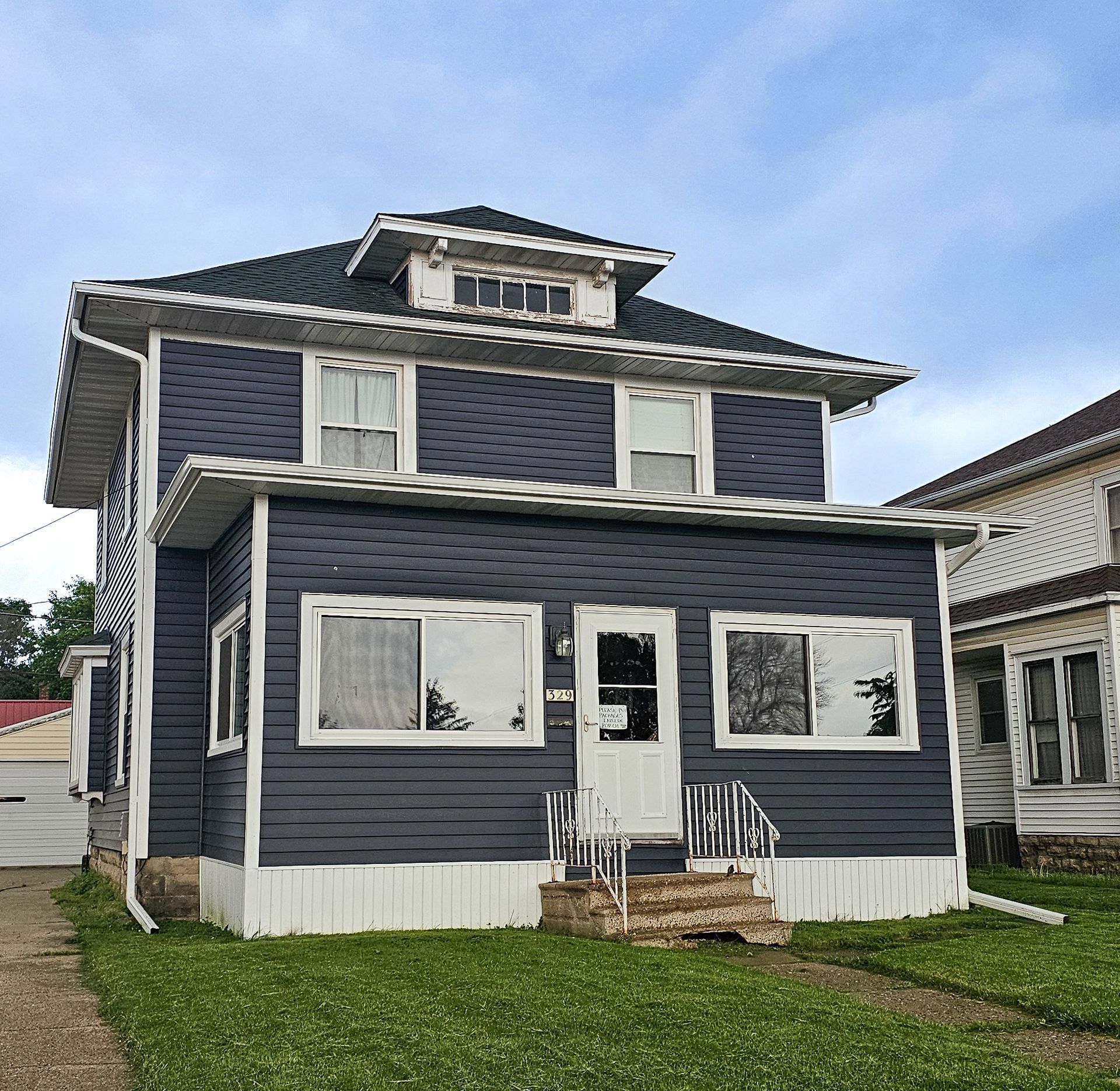 Dark blue house with white trim, siding, and porch, perfect for local siding contractor services.