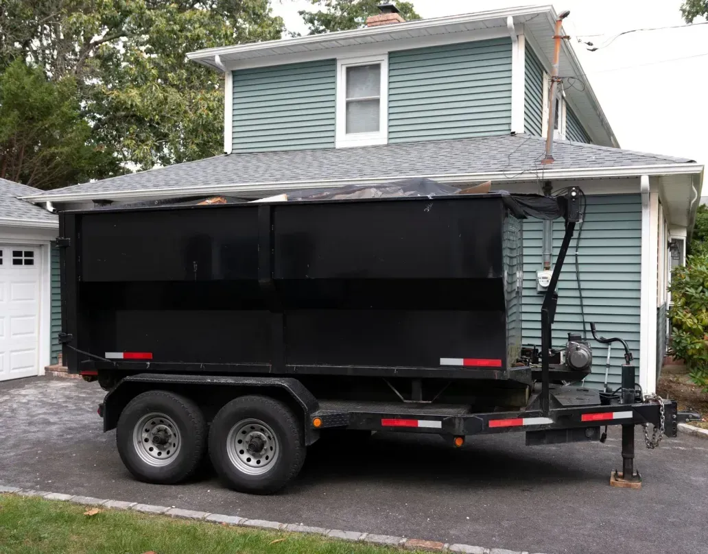 A dumpster trailer is parked in front of a house.