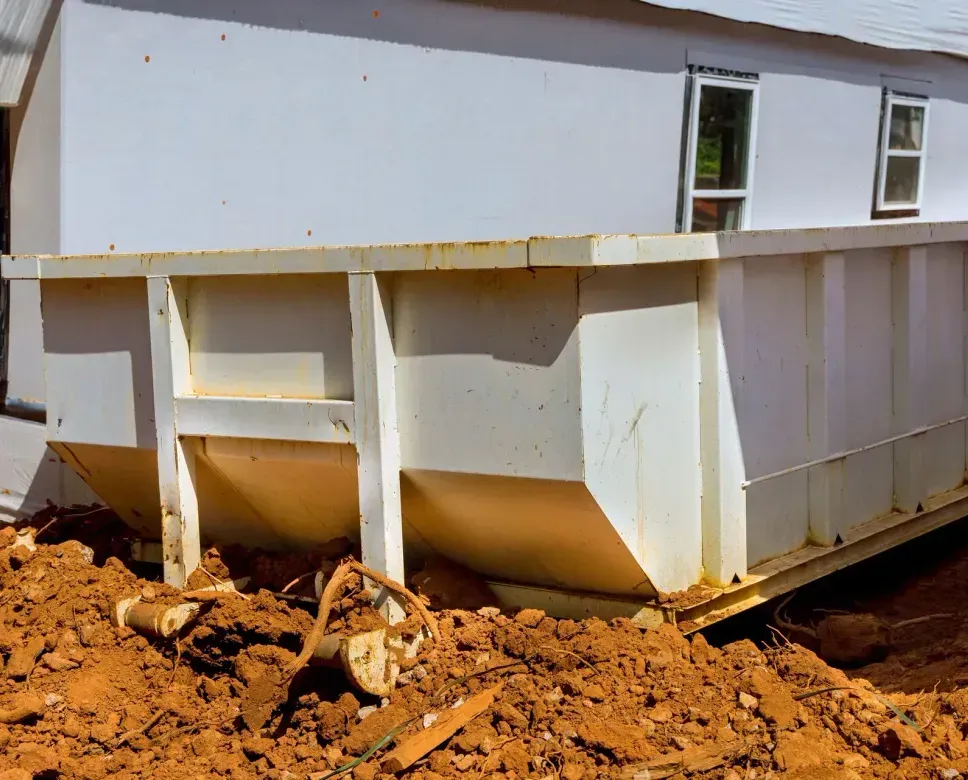 A large white dumpster is sitting in front of a white house