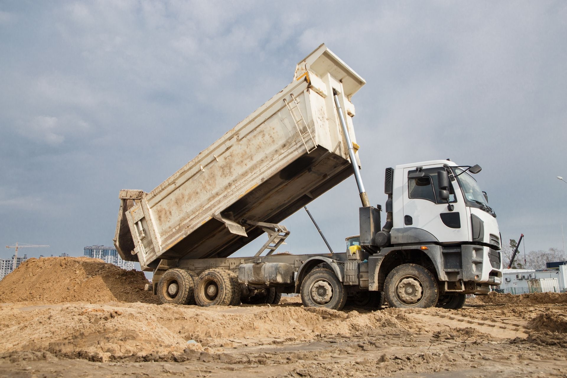 A dump truck is sitting on top of a pile of dirt.
