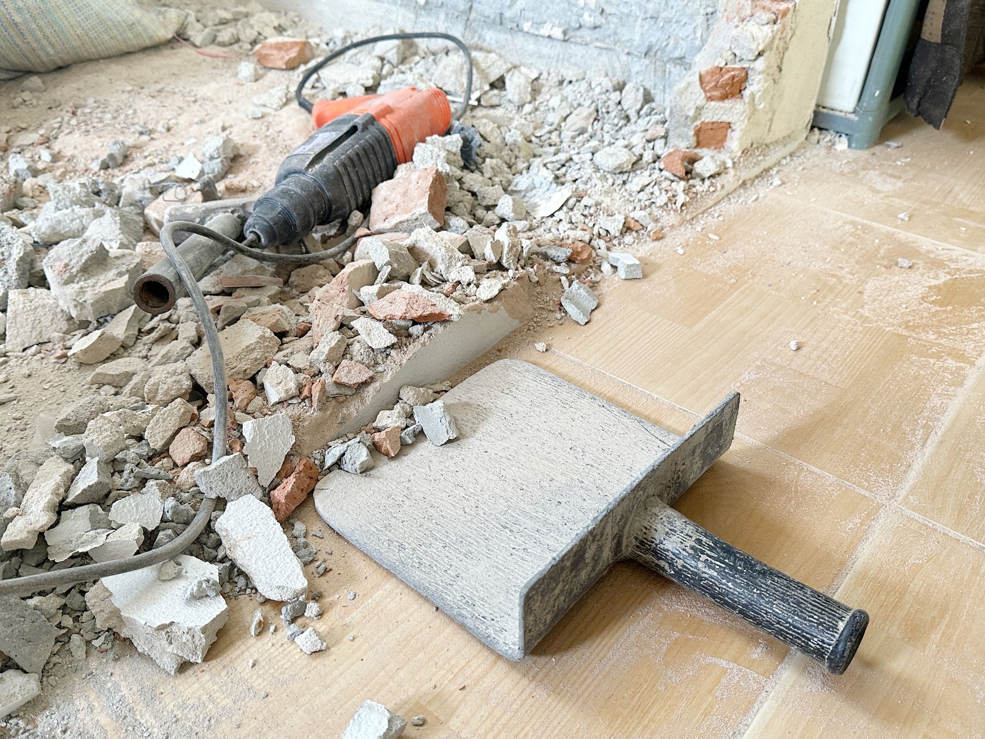 A hammer is laying on the floor next to a shovel.