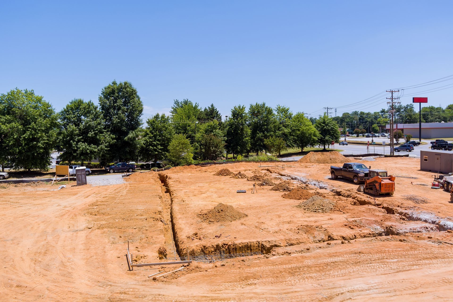 A construction site with a lot of dirt and trees in the background.