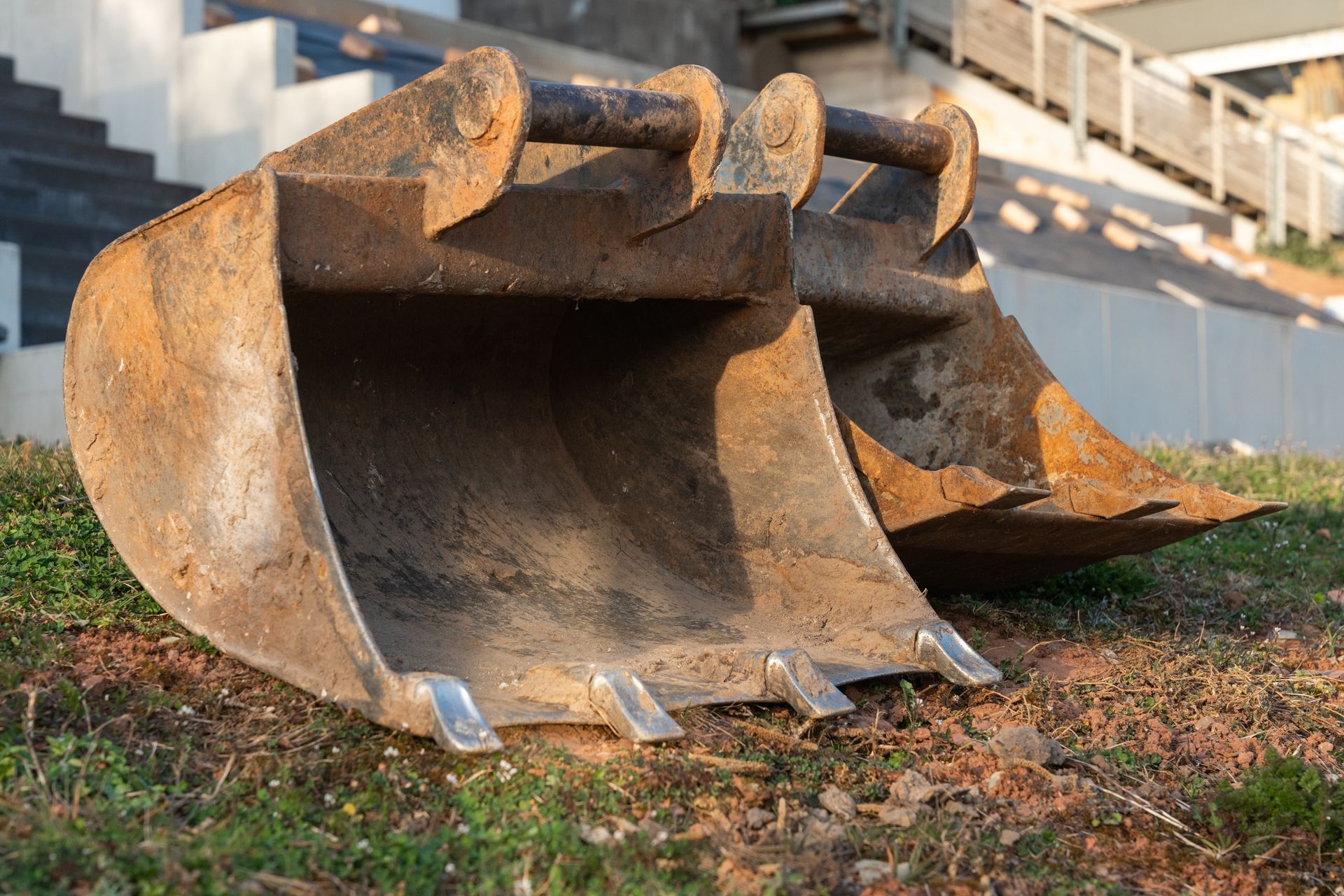 A large excavator bucket is sitting on top of a grassy hill.