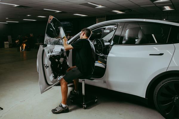 Person working on the open door of a white SUV in a parking garage