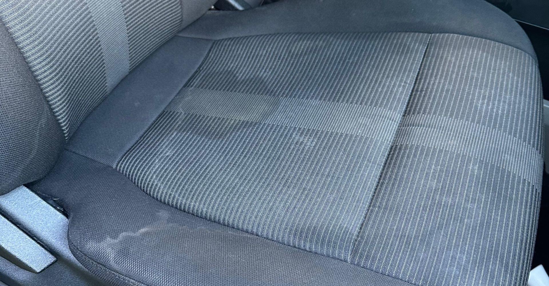 A close-up of a textured, grey upholstered car seat with a patterned fabric design.