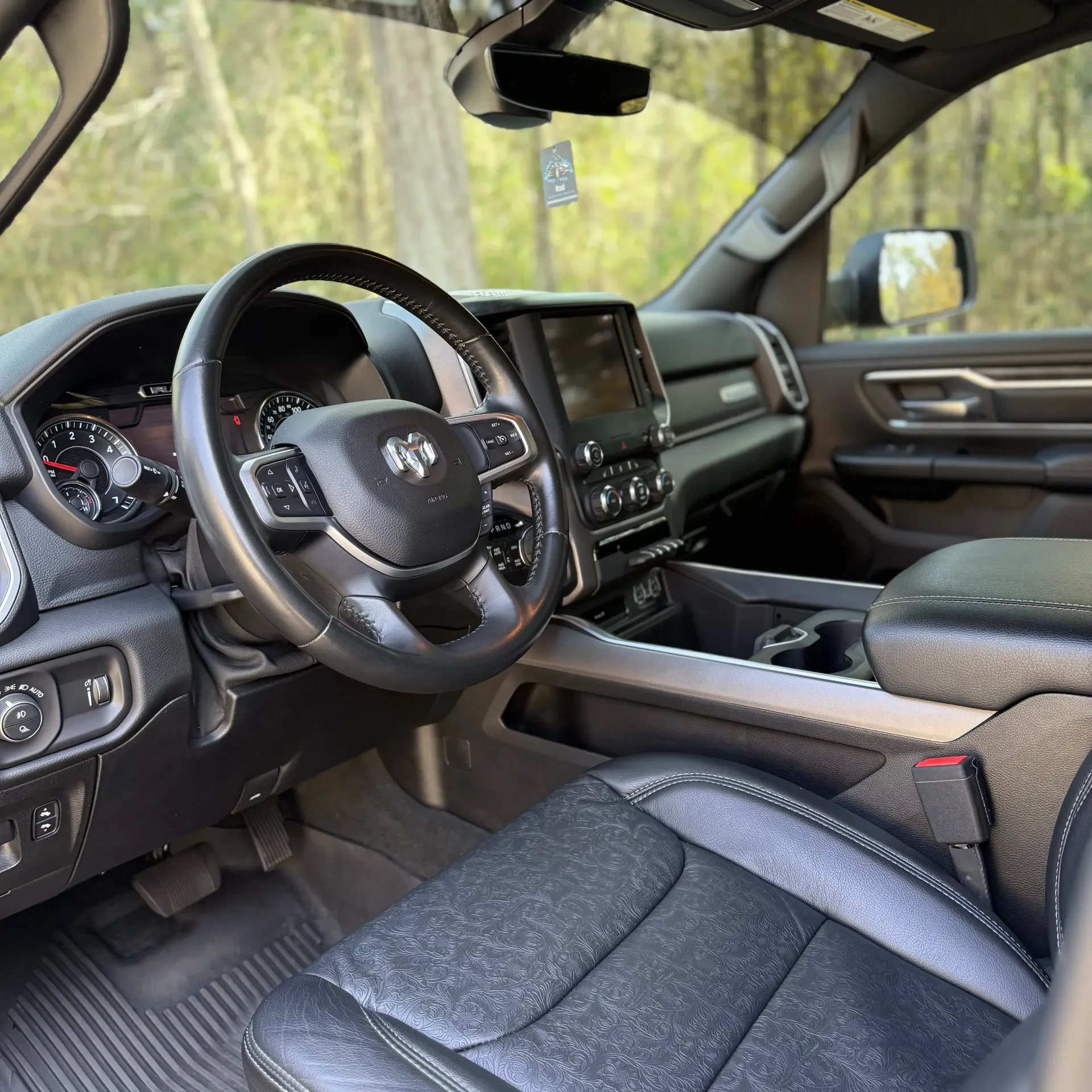 Interior of a modern pickup truck with dark, textured seats, a central steering wheel, and a touchscreen dashboard.