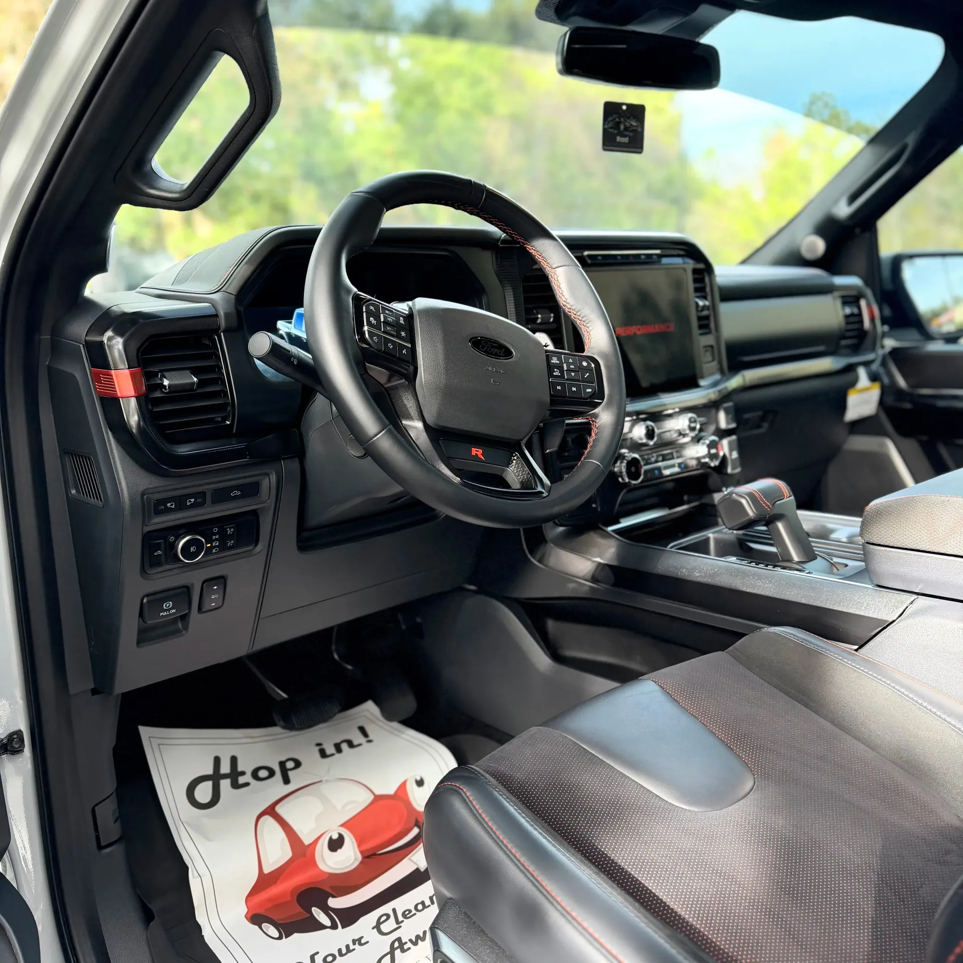 Interior view of a modern truck with a black dashboard, steering wheel, patterned seats, and a