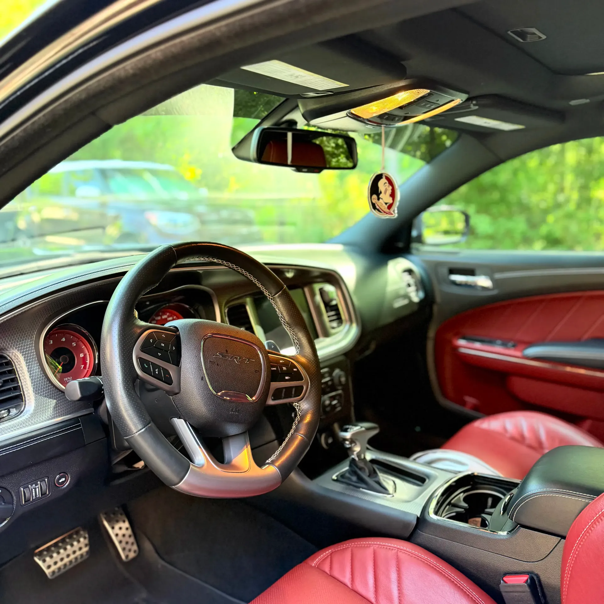 The interior of a Kia vehicle featuring a black leather steering wheel, a digital dashboard, and perforated red seats.