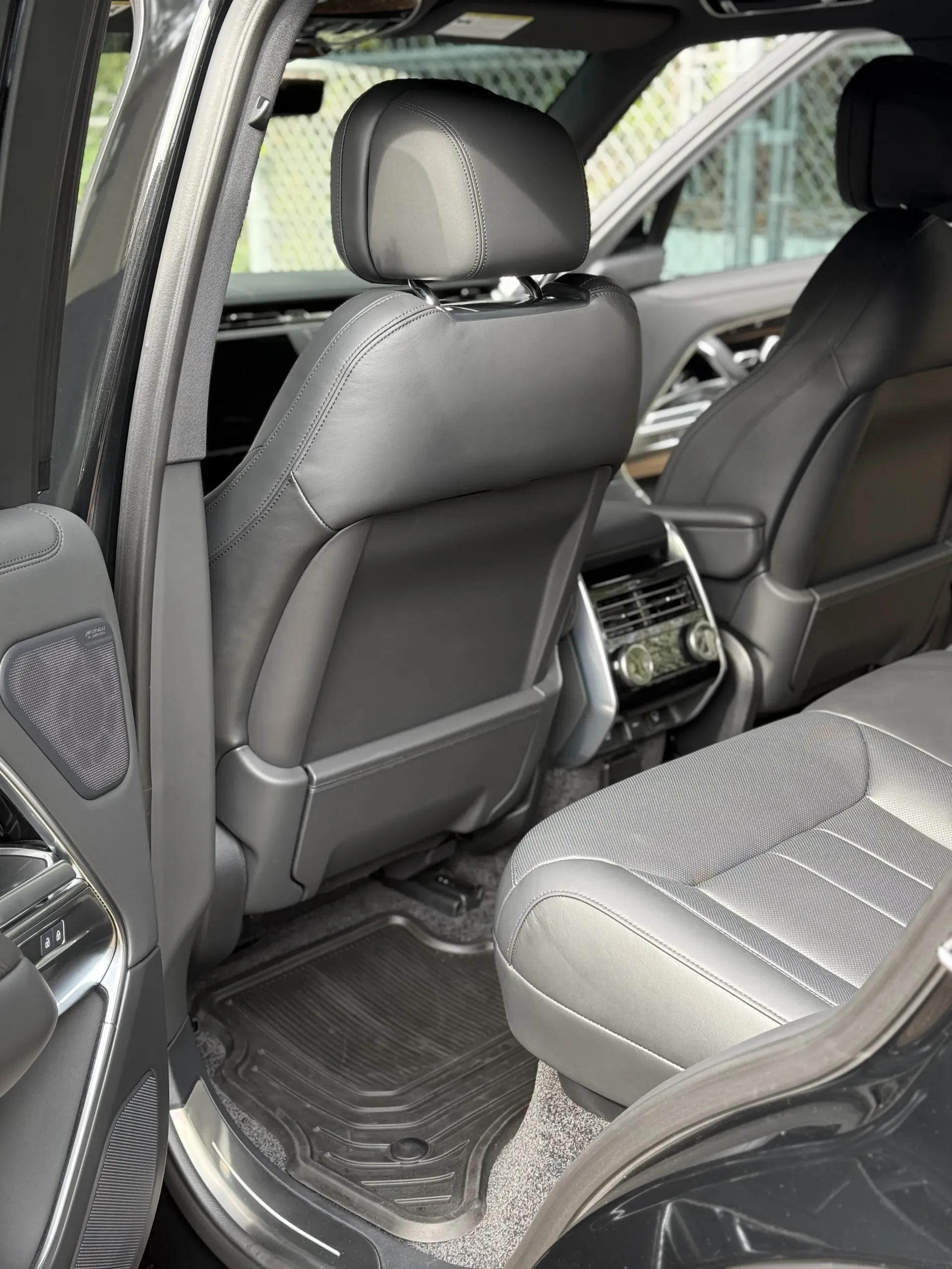 A view inside the back seat of a luxury SUV with black leather, diamond-stitched seats and climate control console.
