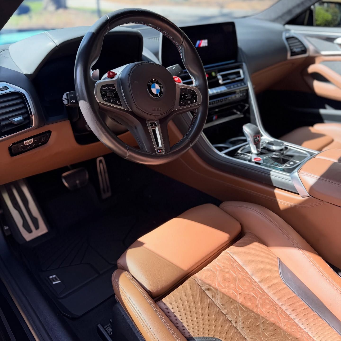 The interior of a car with red leather seats, dark interior trim, and black rubber floor mats.