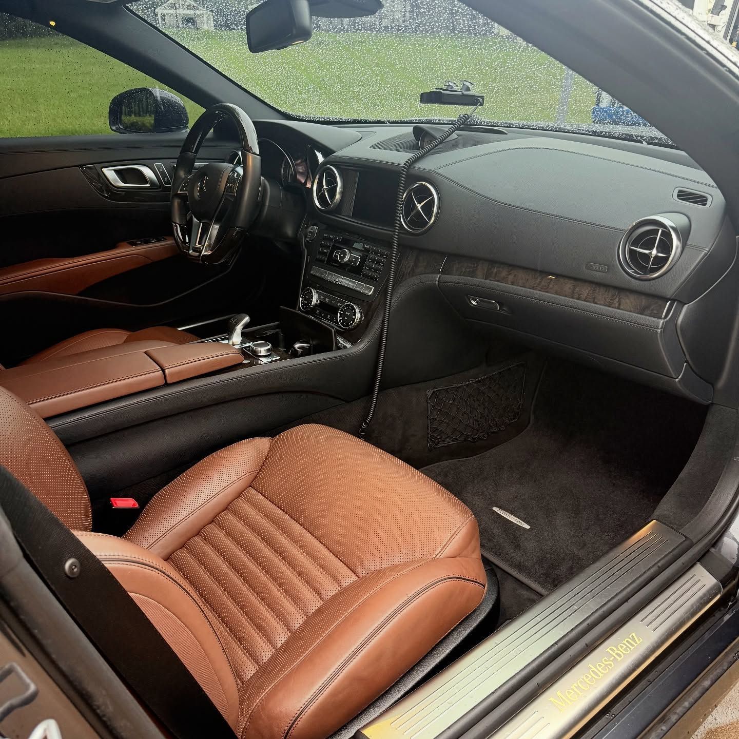 A view inside the back seat of a luxury SUV with black leather, diamond-stitched seats and climate control console.