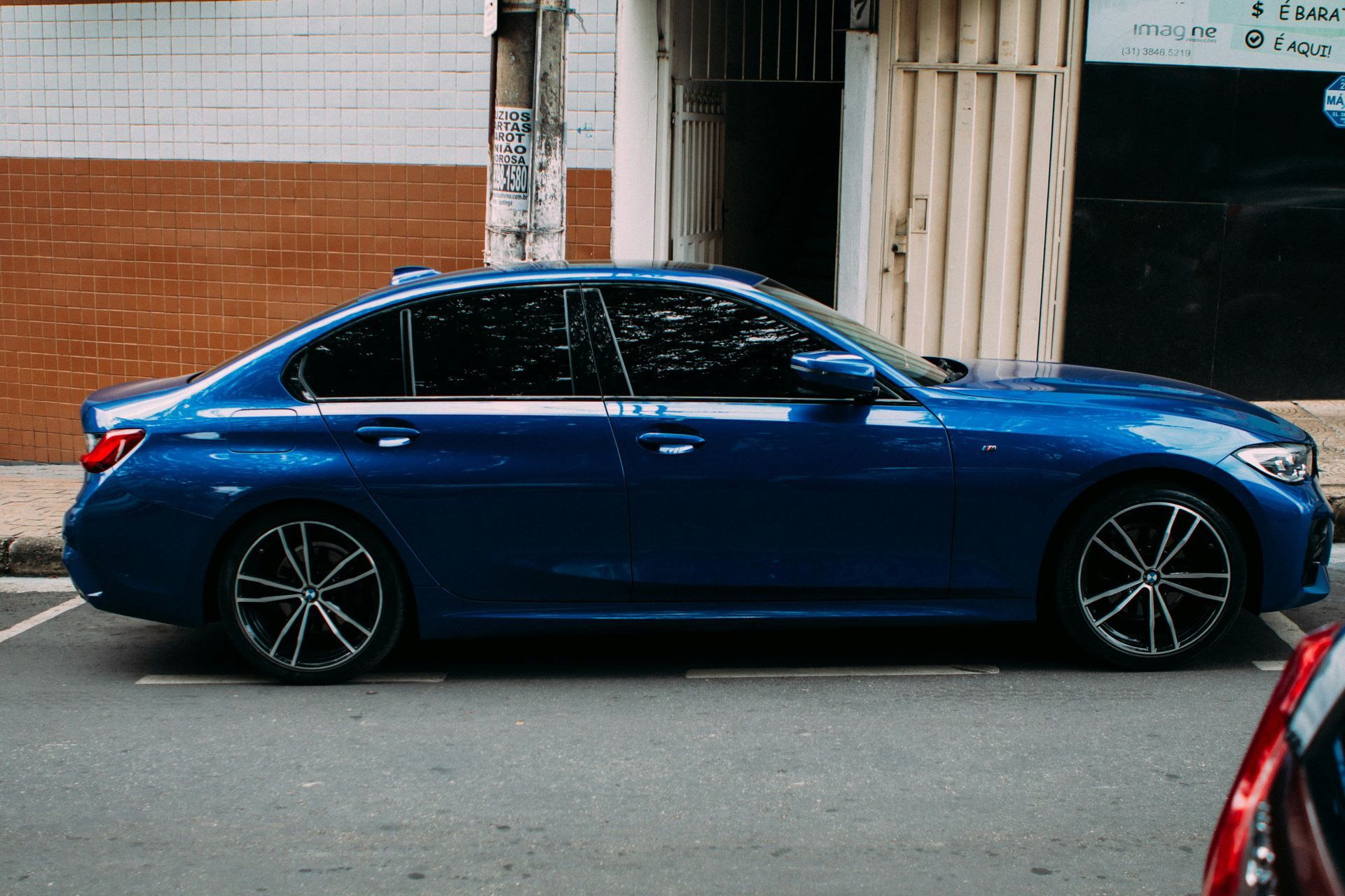 BMW sedan receiving professional ceramic window tint installation with dark tinted windows, glossy black paint, and premium detailing finish at RydrDie Auto Detailing.