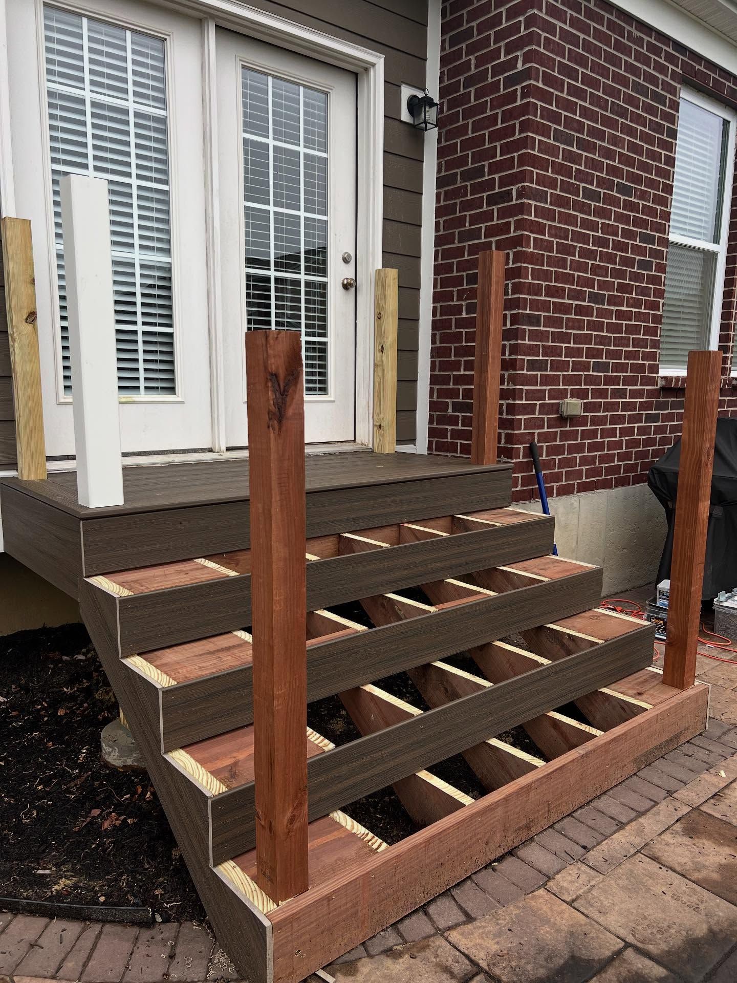 Deck stairs under construction with exposed framing and several vertical posts.