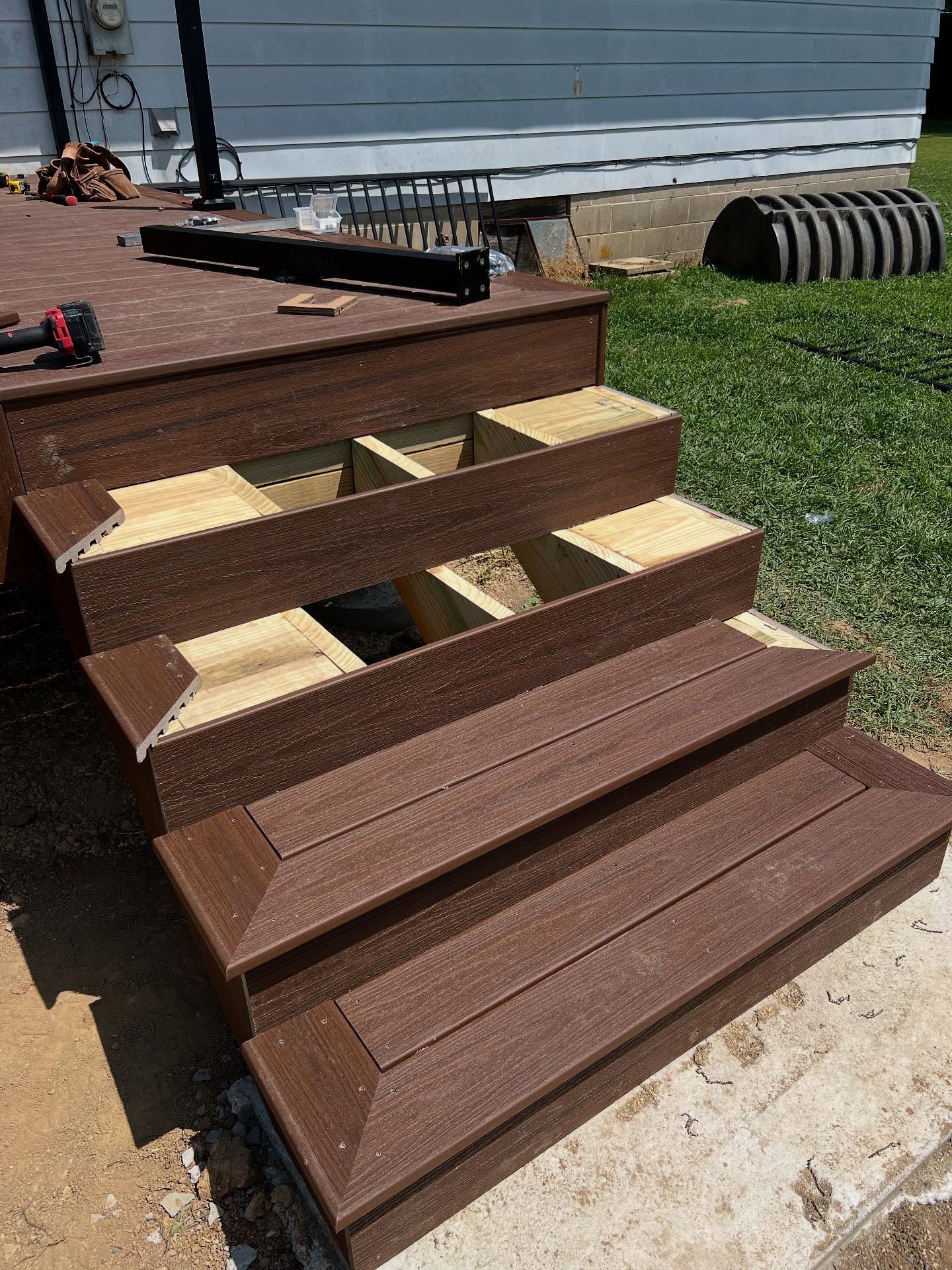Composite deck steps under construction, brown and tan, outdoors.