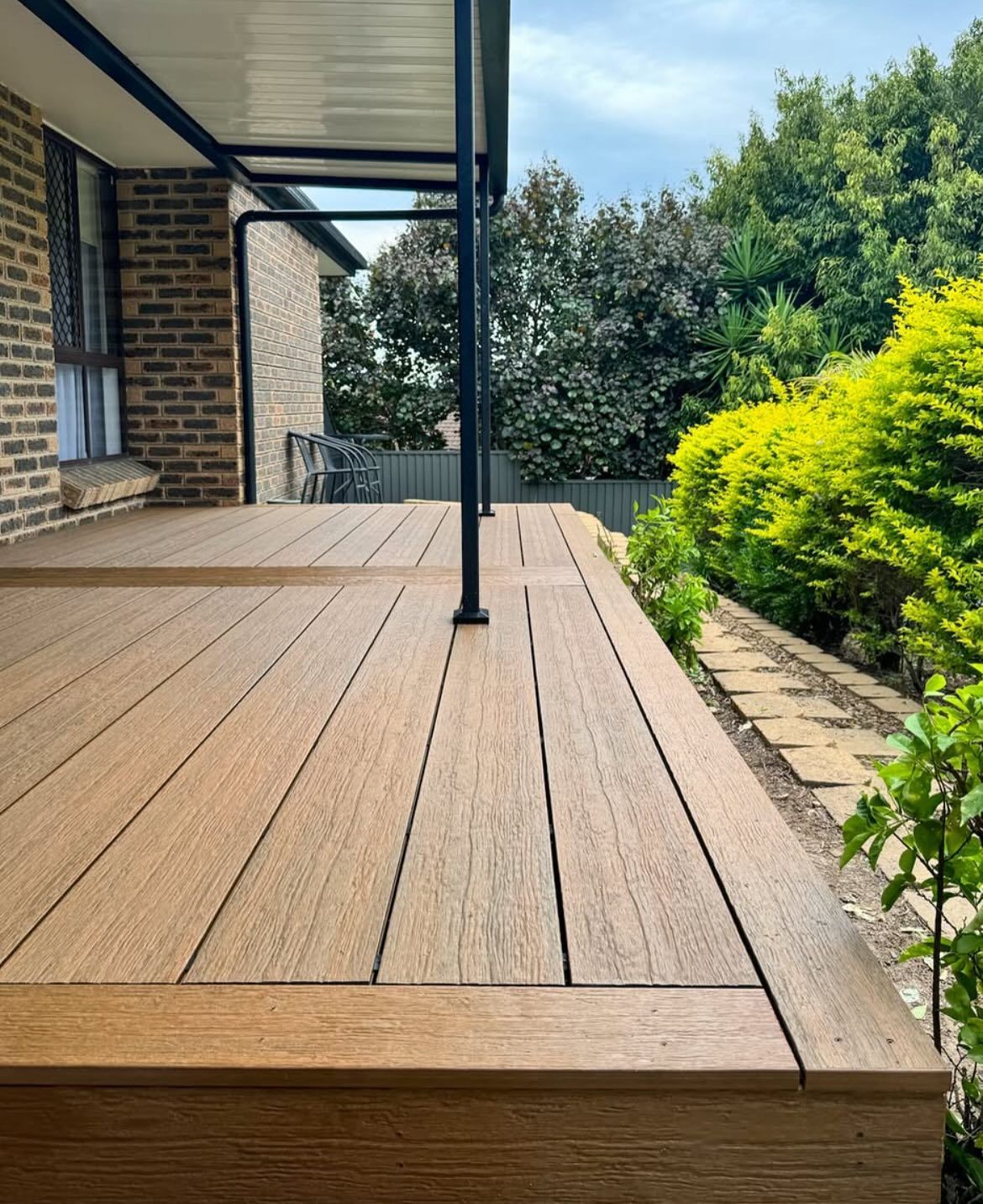 Wooden deck with canopy, overlooking a garden.