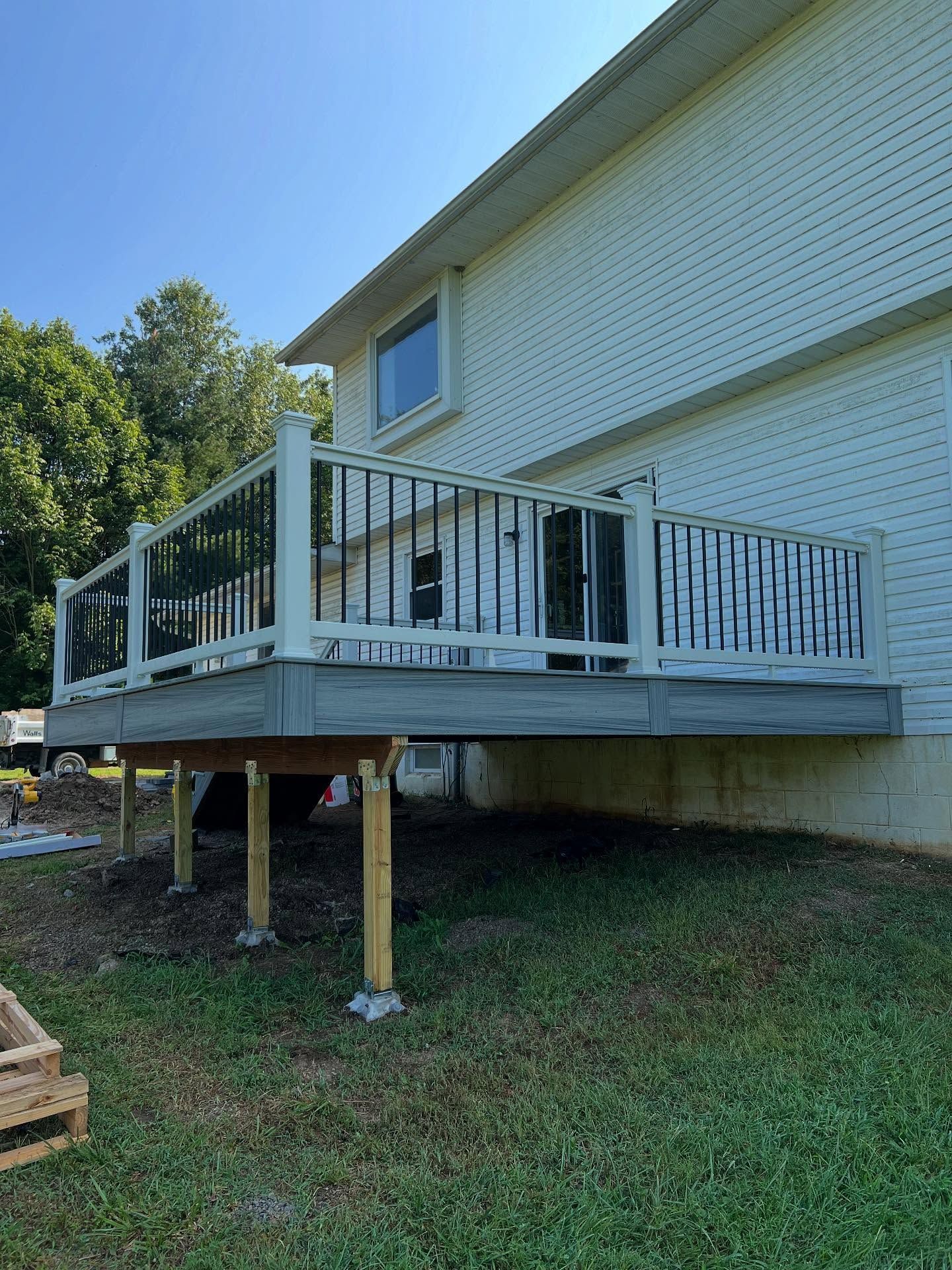 A two-story house with a new elevated deck, gray deck boards, white railings, and black balusters.
