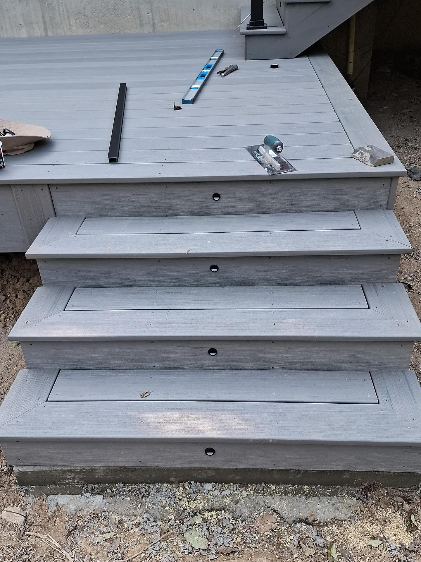 Gray composite deck steps with recessed lighting.