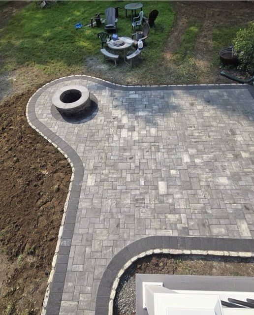 Stone retaining wall with stairs leading to a beige and brown building against a cloudy sky.