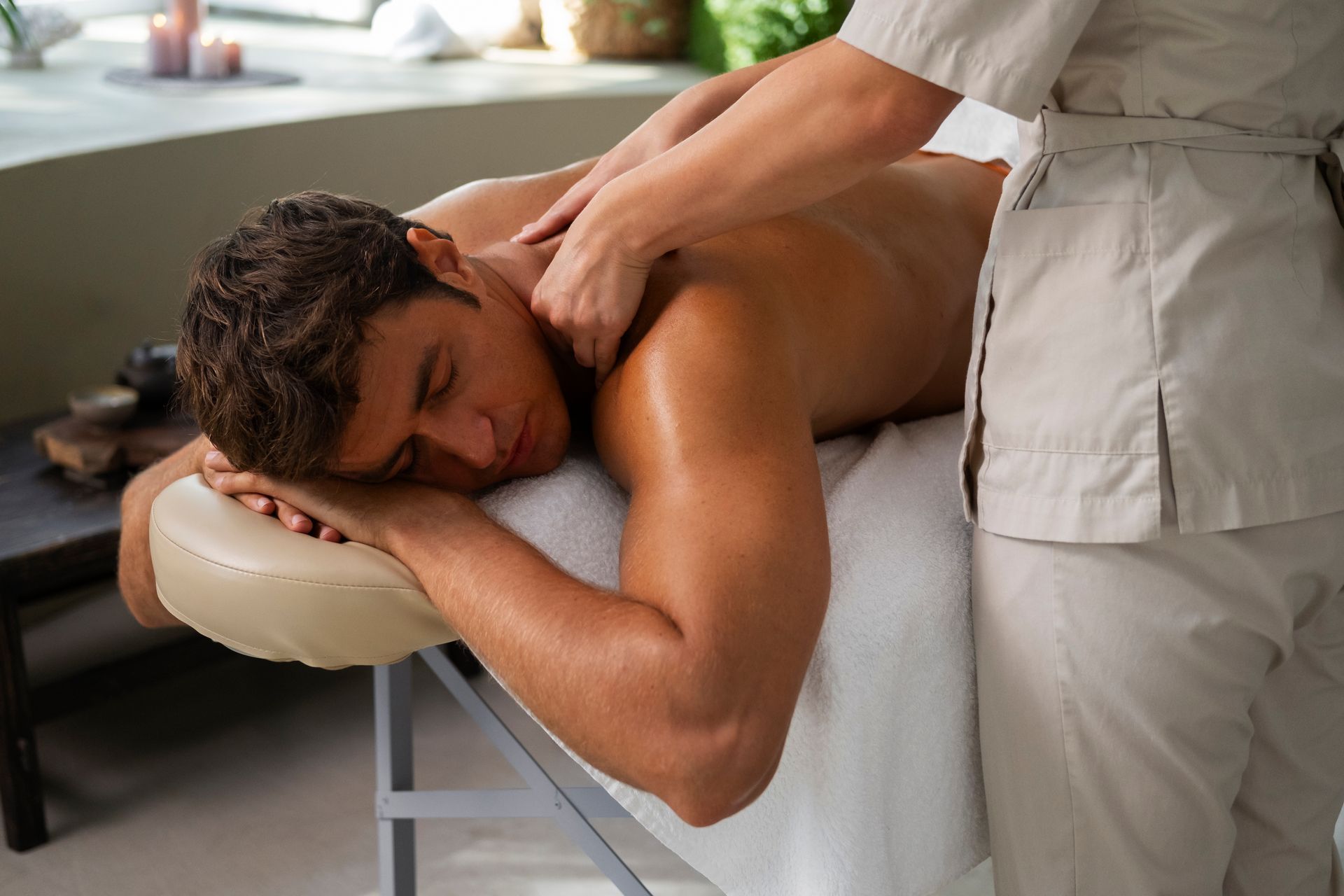 Un homme reçoit un massage du dos dans un spa, face contre terre sur une table de massage.