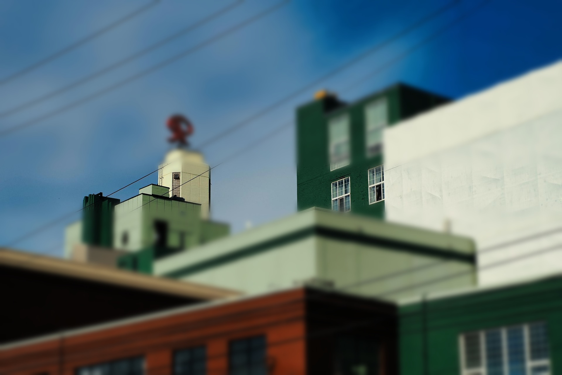 Buildings with varying colors and heights, some with windows, against a blue sky with power lines.