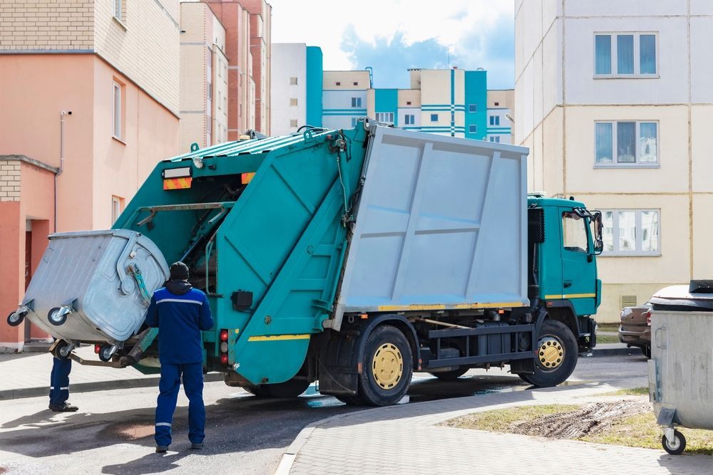 A garbage truck is parked in front of a building.