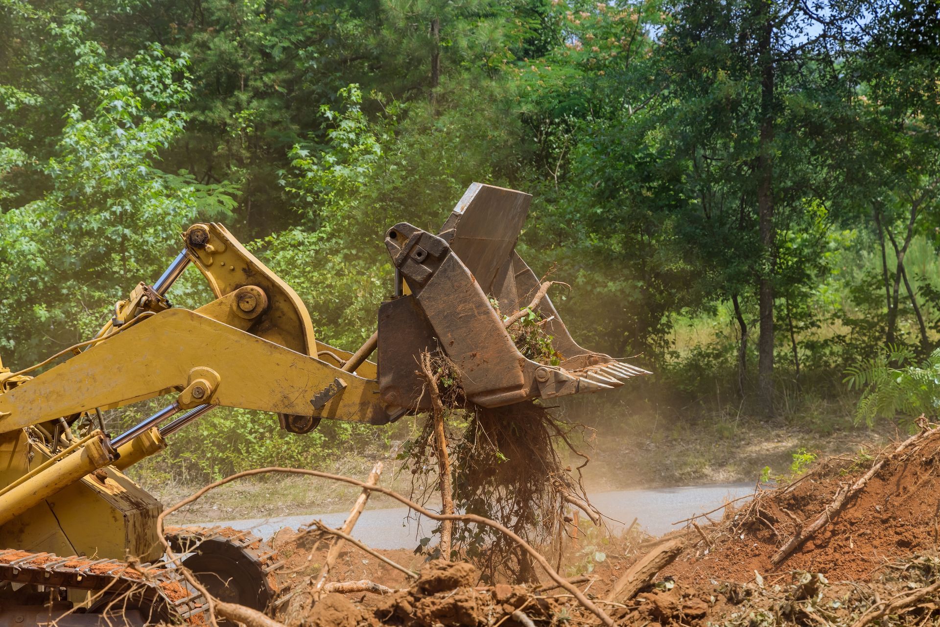 A bulldozer is moving dirt on a road in the woods.