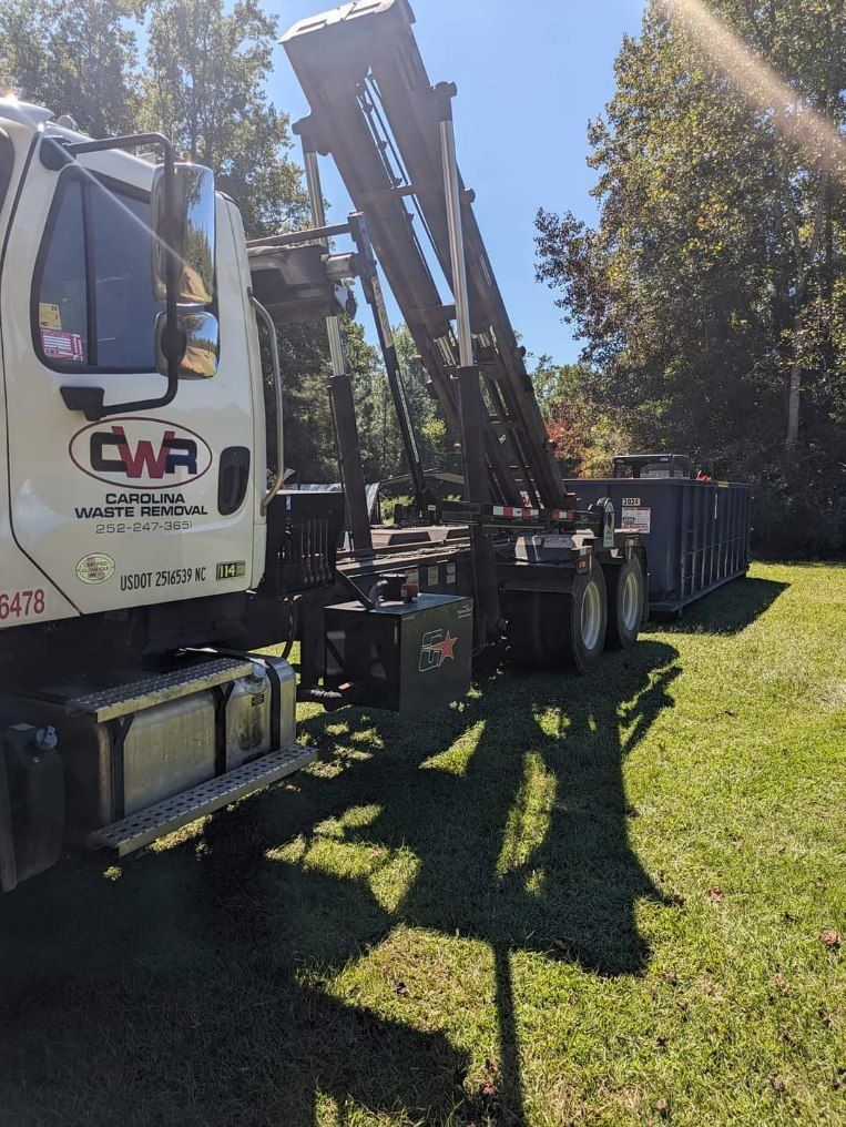 A white truck with a crane on the back is parked in a grassy field.