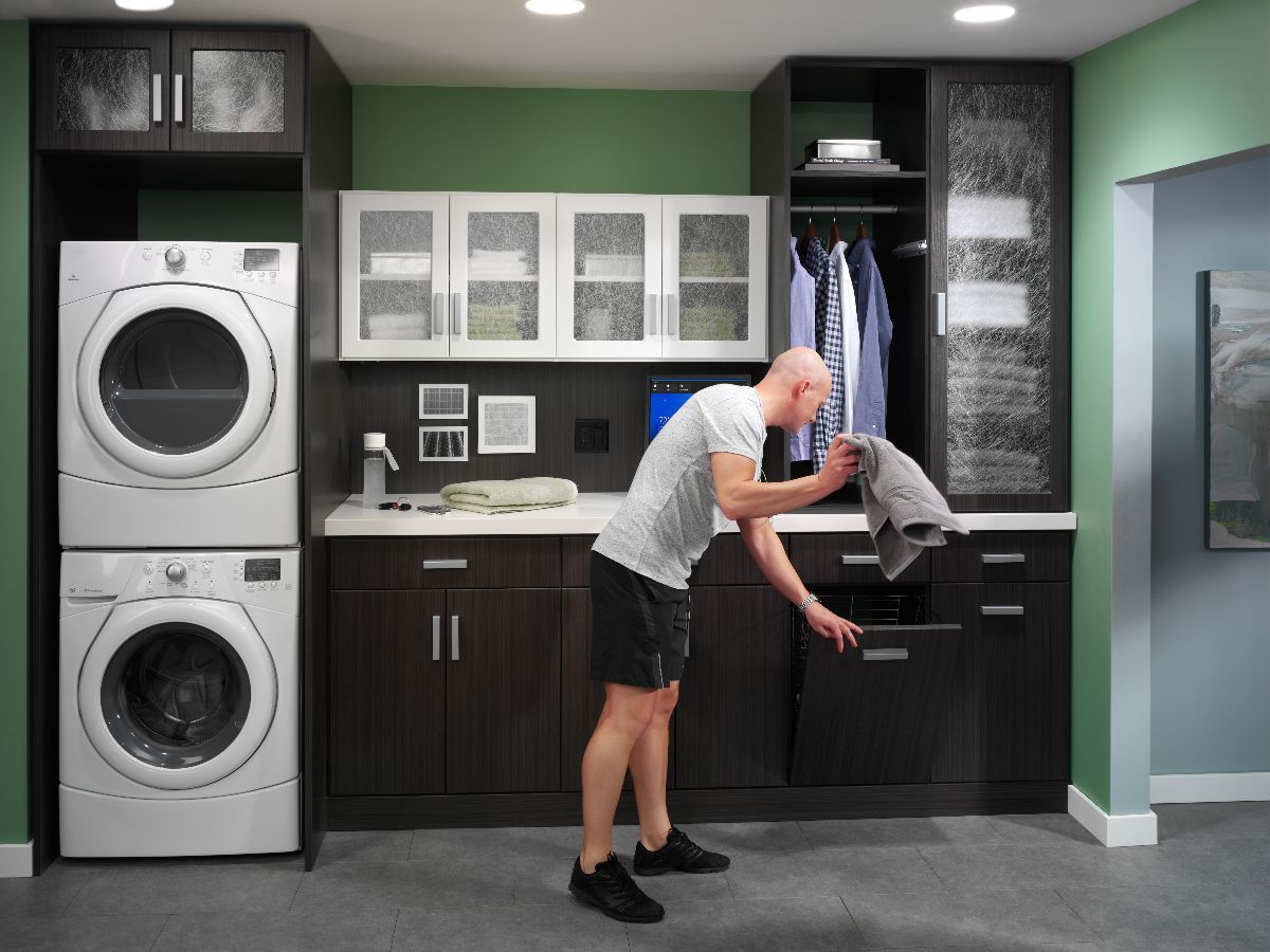 A man is standing in a laundry room next to a washer and dryer.