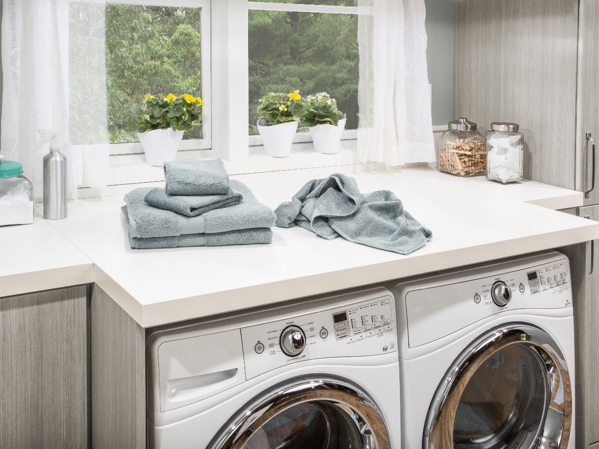 A laundry room with a washer and dryer and towels on the counter.