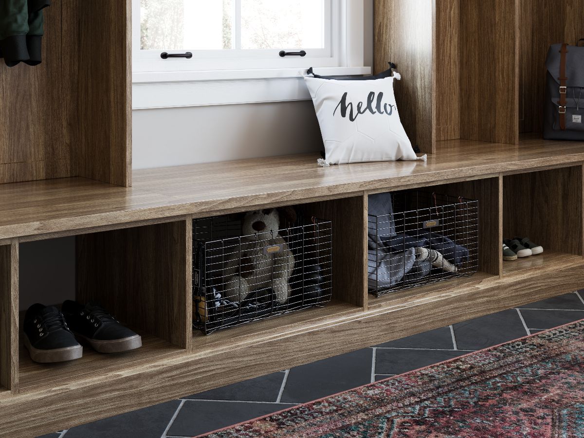A wooden bench with a pillow and baskets in a hallway.