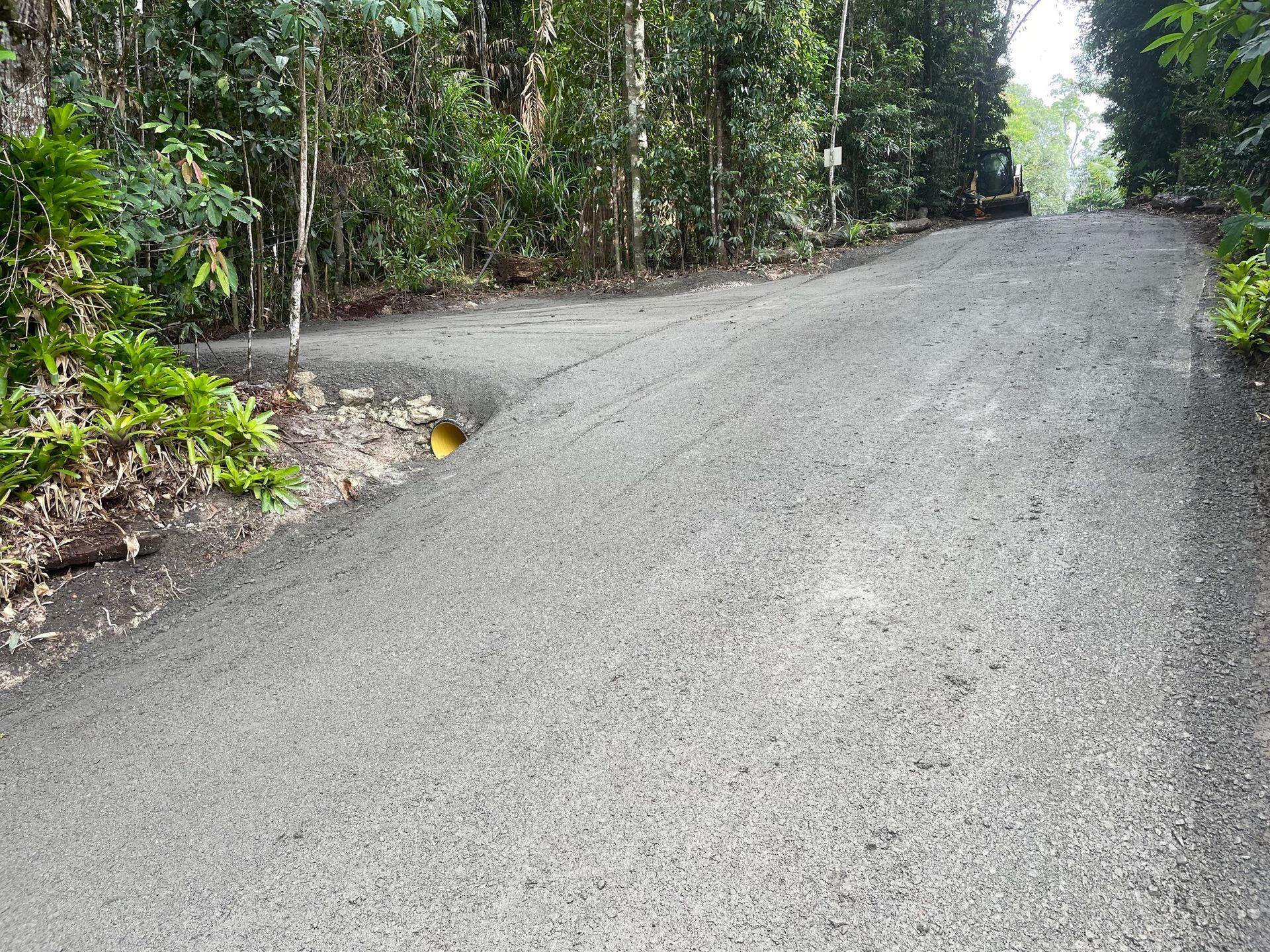 A Brush Spreading Black Sealant on a Dark Asphalt Surface — Kuranda Landscape Supplies in Kuranda, QLD