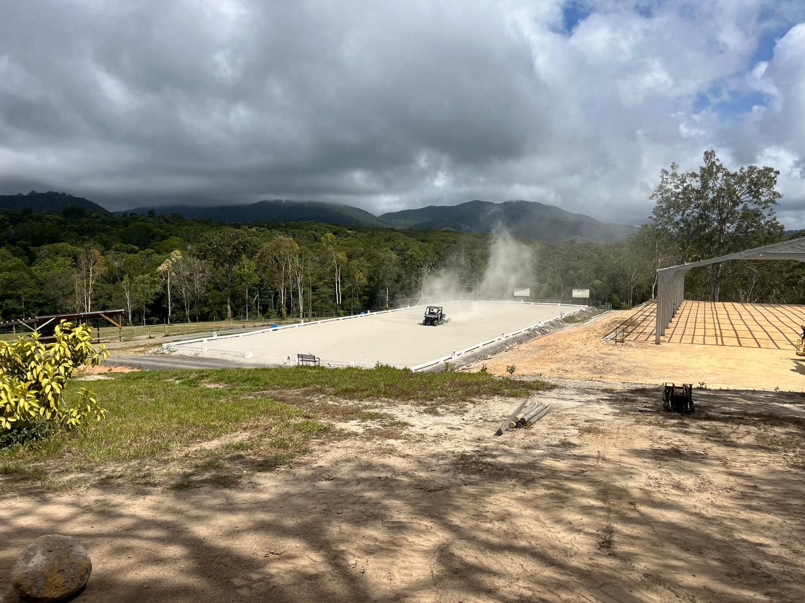 Off-road vehicle driving on a dusty track, mountains and trees in the background under a cloudy sky — Kuranda Landscape Supplies in Kuranda, QLD