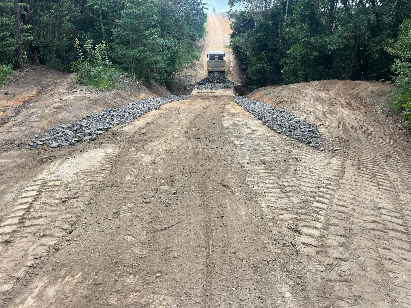 Dirt road sloping upward, flanked by rocks and trees. A truck is at the top — Kuranda Landscape Supplies in Kuranda, QLD