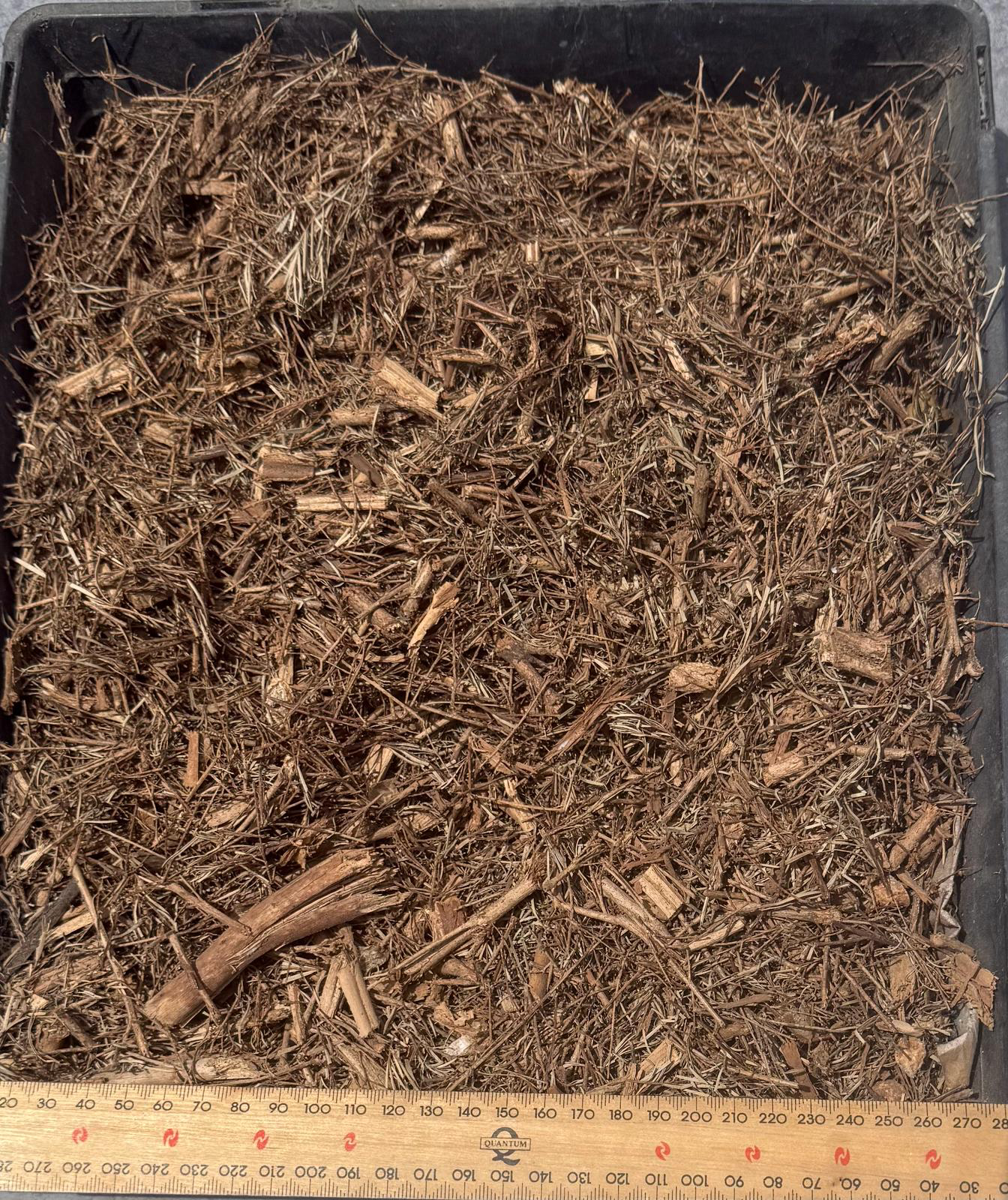 Wood mulch in a black container with a ruler at the bottom — Kuranda Landscape Supplies in Kuranda, QLD