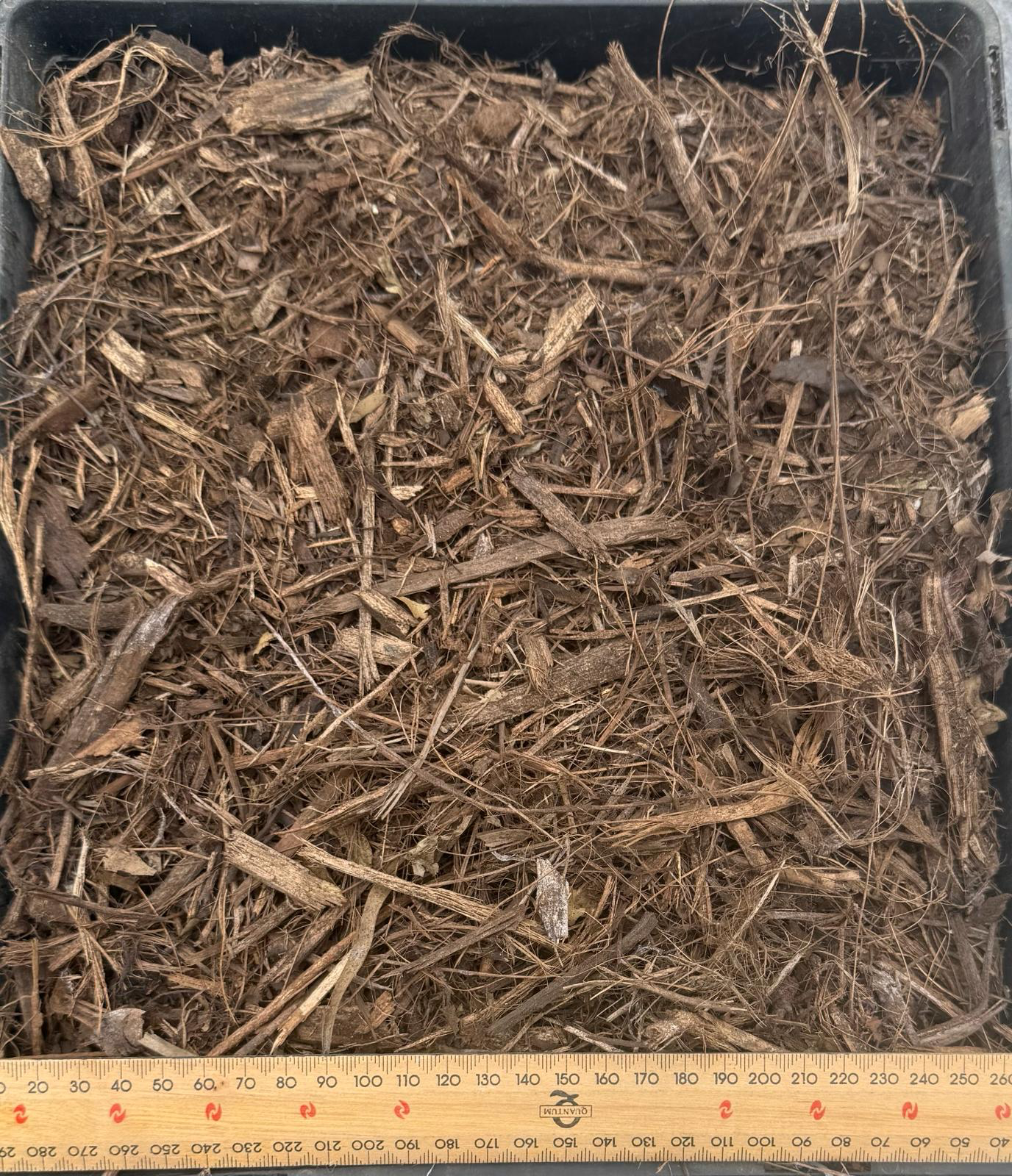 Brown mulch in a square black container with a ruler at the bottom — Kuranda Landscape Supplies in Kuranda, QLD